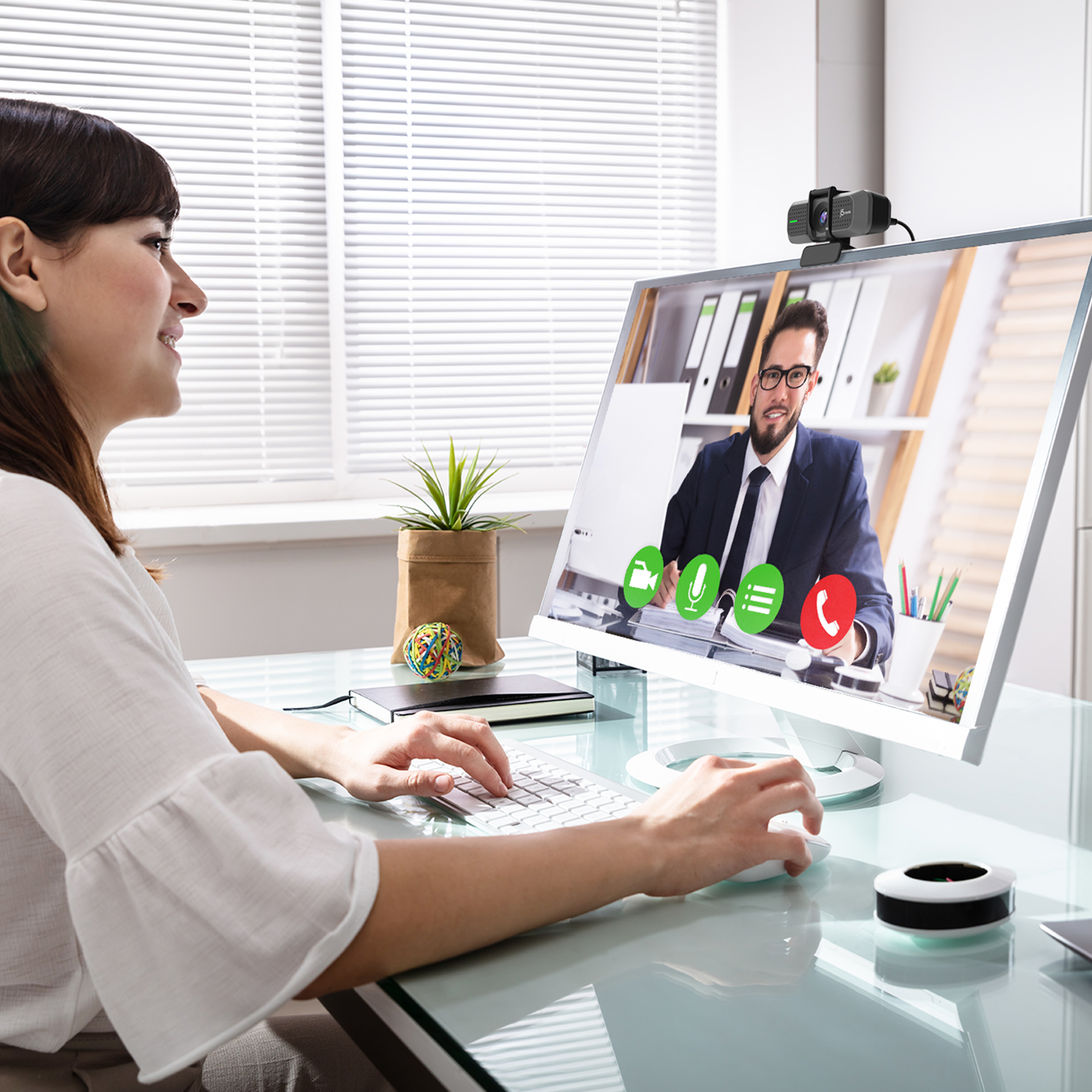 Frau bei Videoanruf am Desktop-Computer mit Webcam, moderner Schreibtisch.