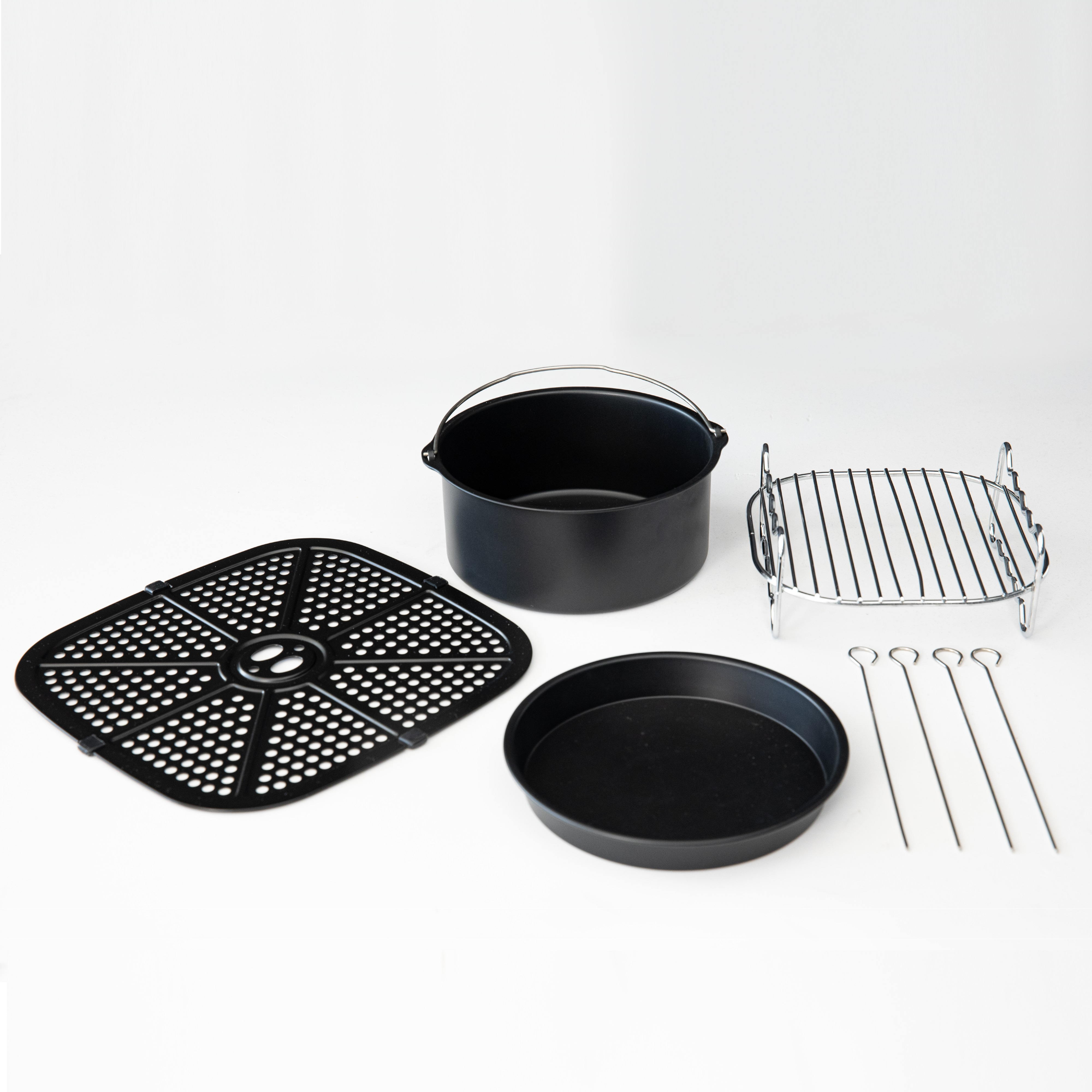 Airfryer-Komponenten: schwarzer Korb, Pfanne, Grill und Spieße, angeordnet auf weißer Oberfläche.
