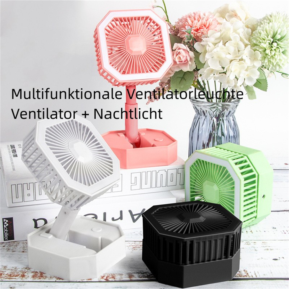 Cuatro pequeños ventiladores. Uno rosa, uno verde, uno blanco, uno negro, todos sobre una superficie blanca con libros.