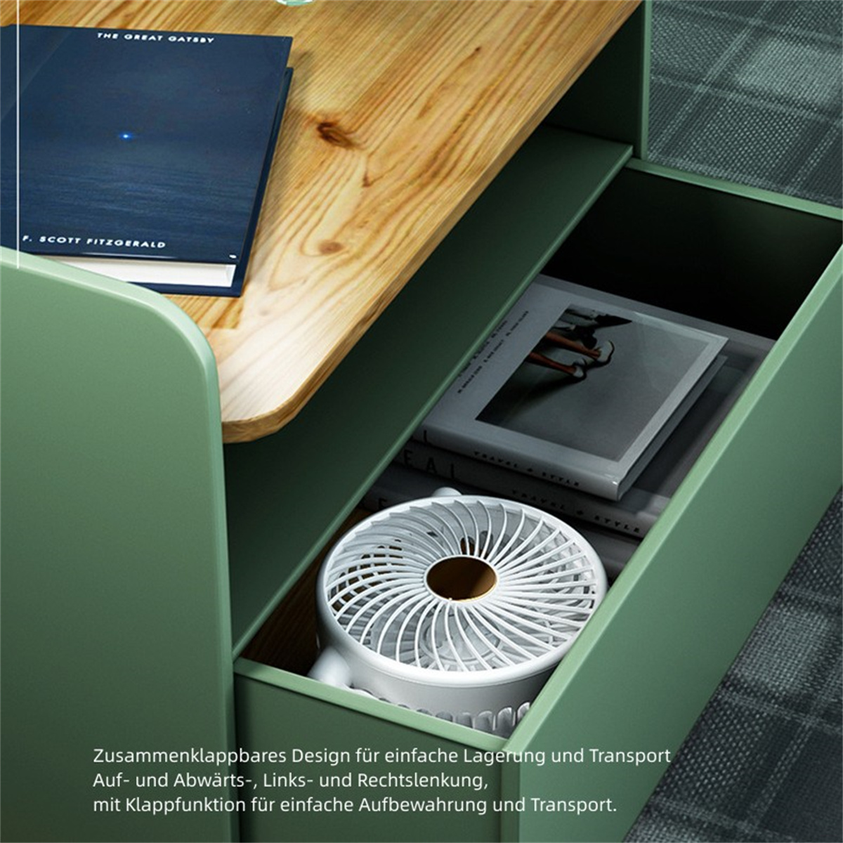 Un escritorio con un cajón, libros y un ventilador blanco. El escritorio es verde.