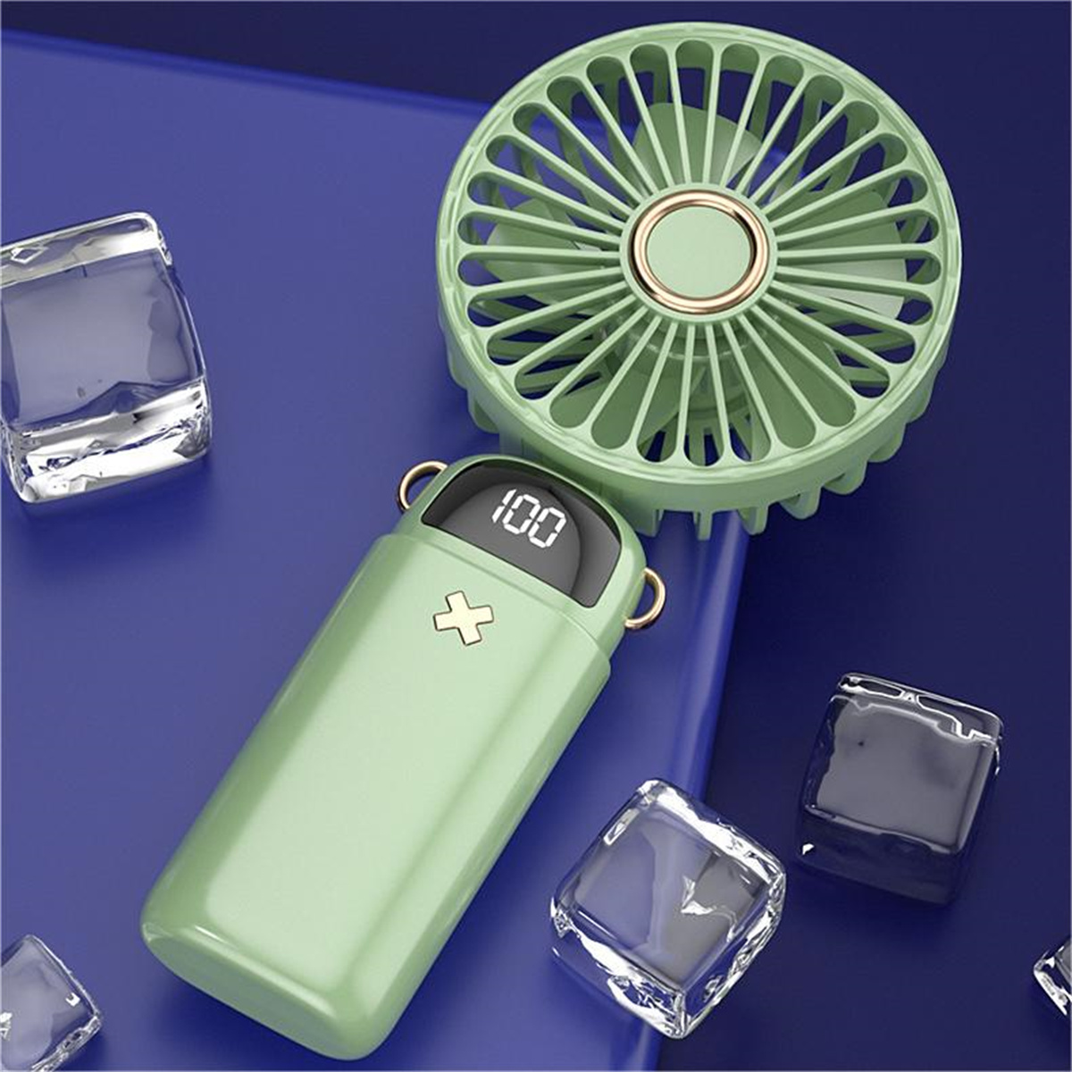 Un ventilador verde portátil con pantalla digital y cubitos de hielo en una superficie azul.