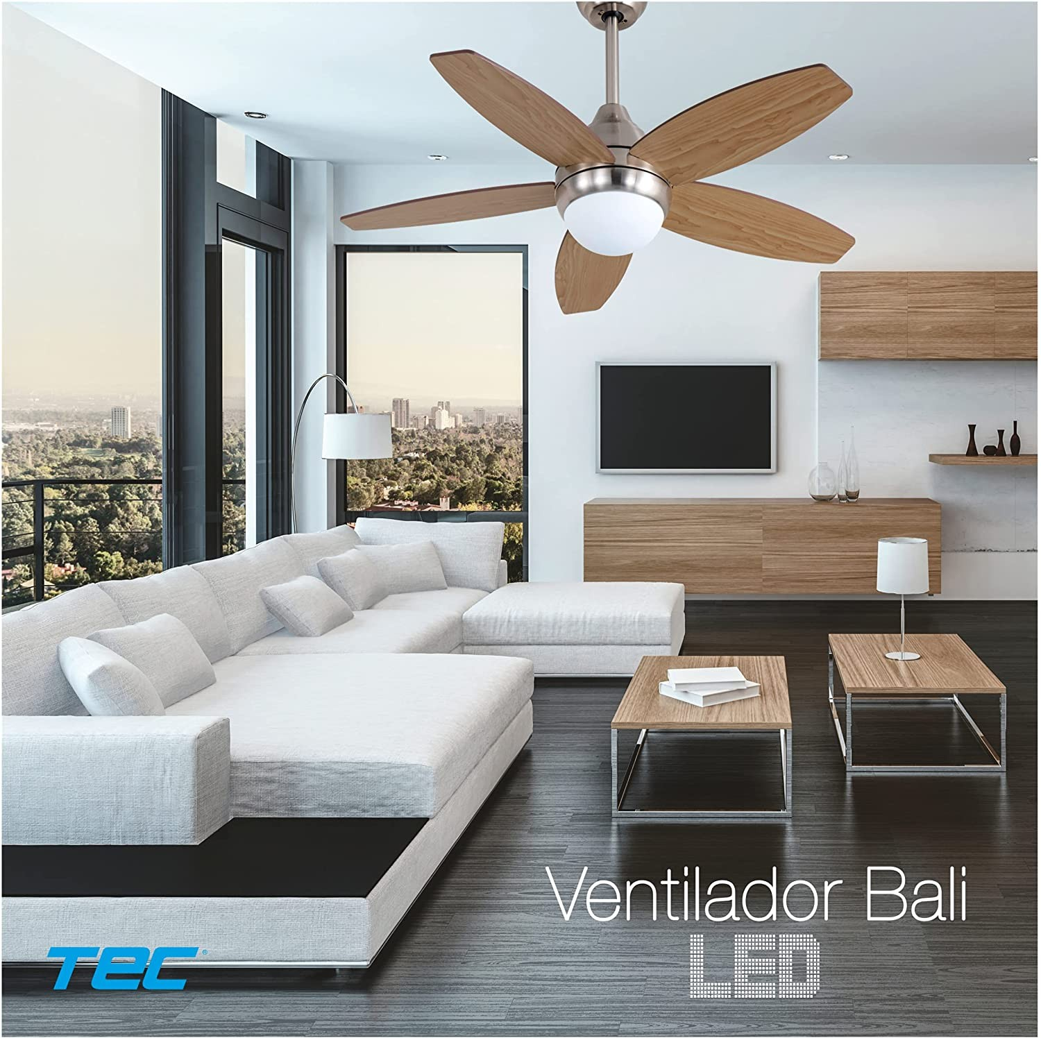 Salón moderno con ventilador de techo, sofá blanco y vista de una ciudad.