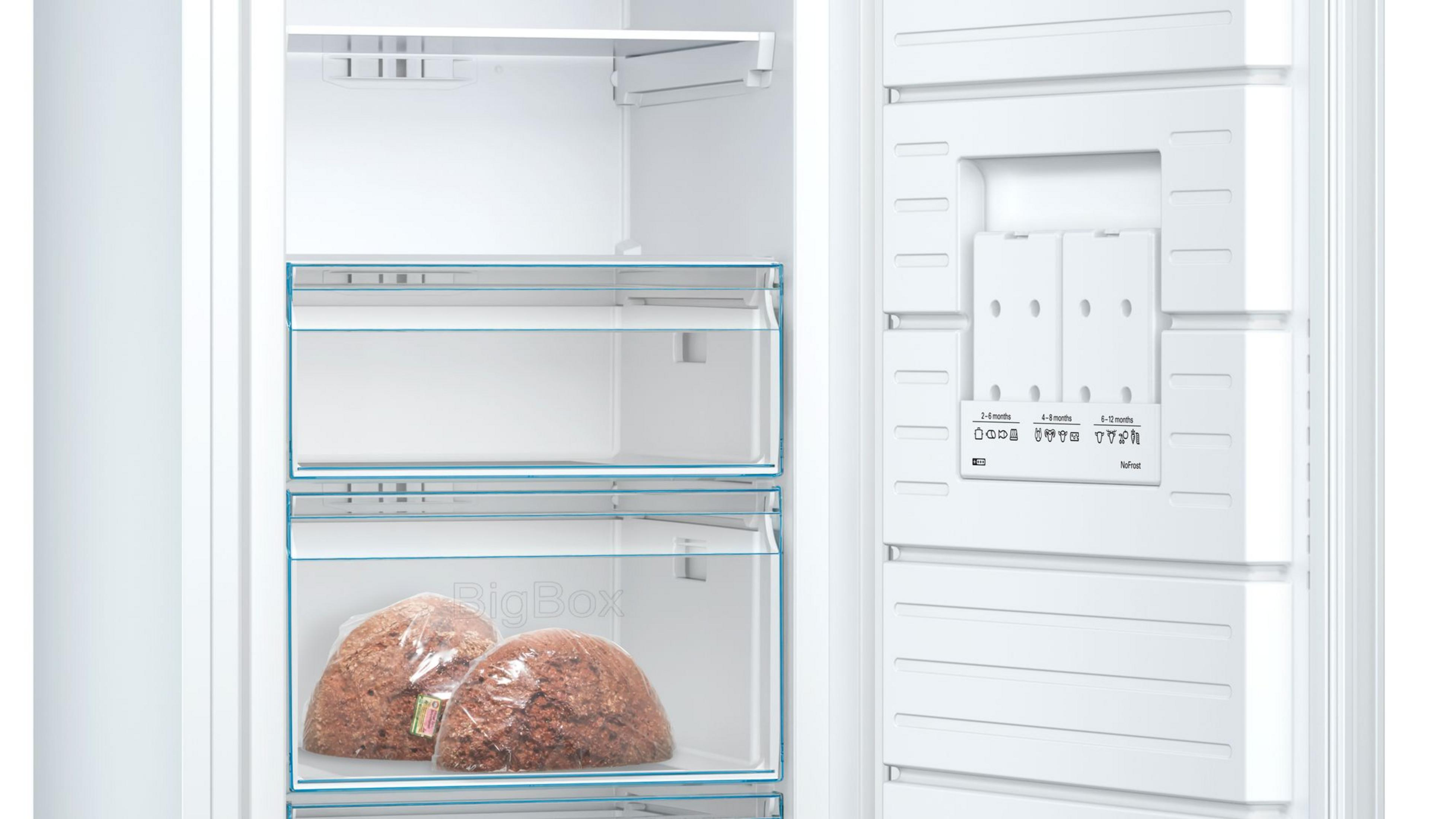 In einem weißen Kühlschrank mit Regalen, Schubladen und Lebensmittelpaketen. Text und Etiketten sind sichtbar.