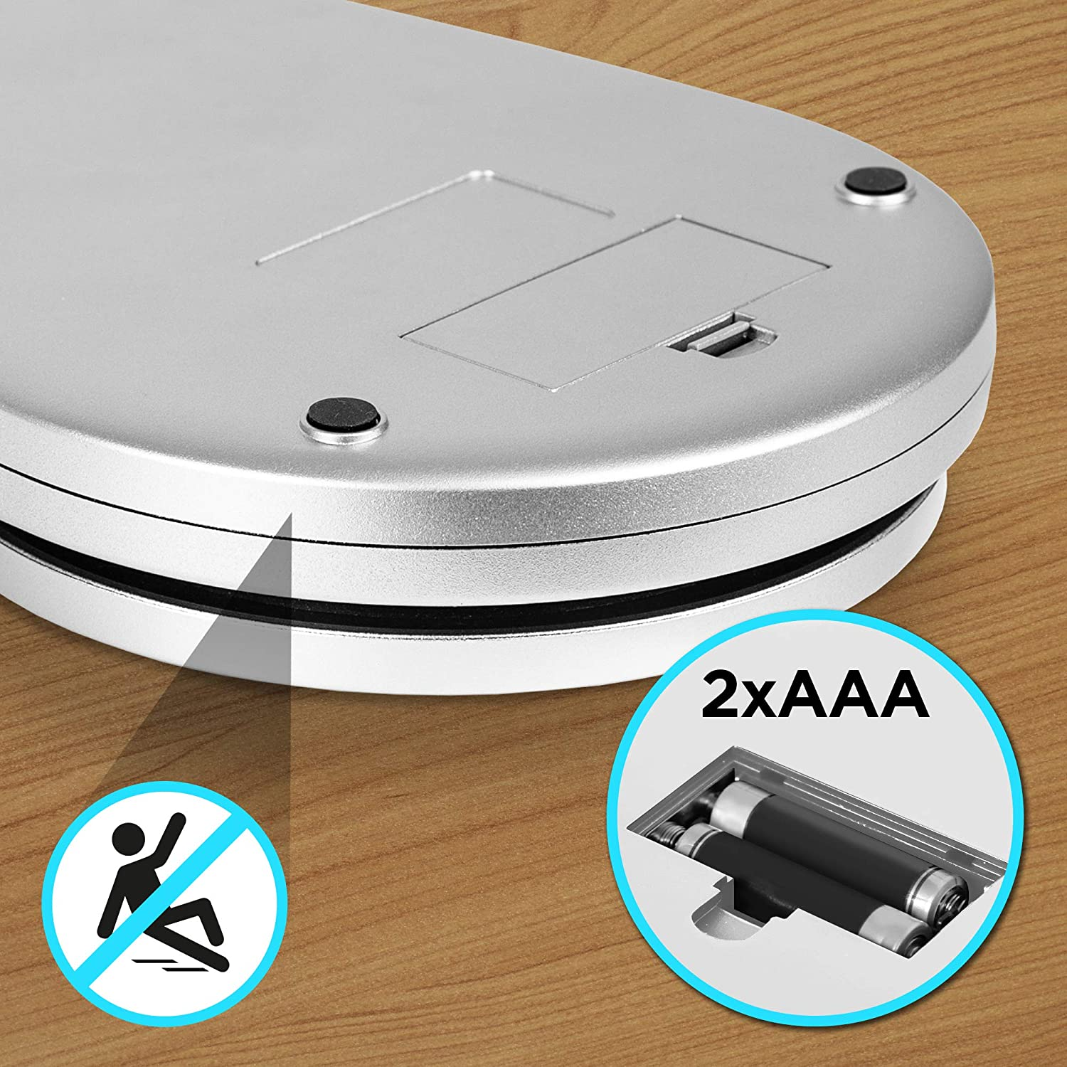 Eine silberne Digitalwaage mit Batterien und einem Warnhinweis zum Ausrutschen auf Holzoberfläche.