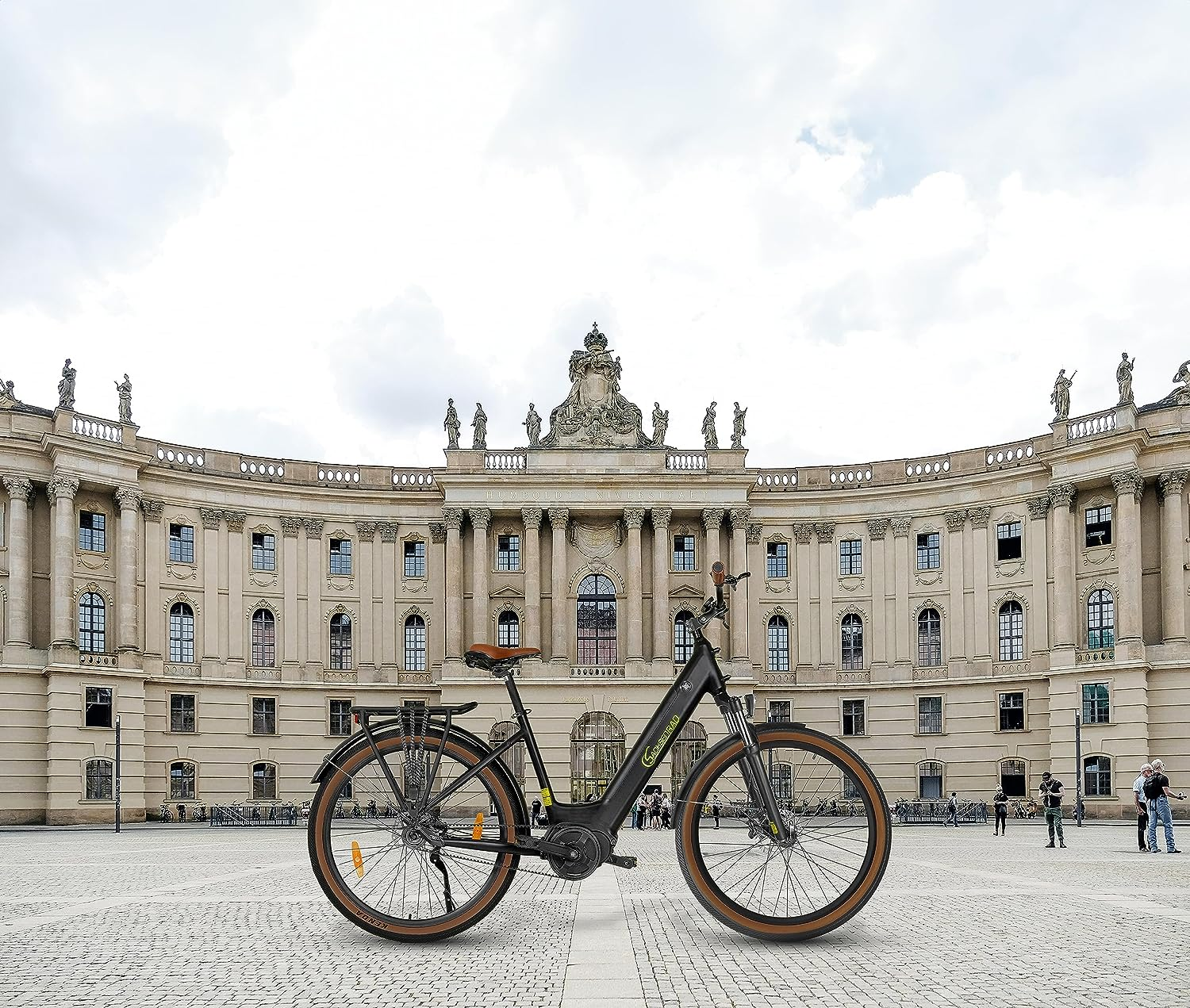 Schwarzes Elektrofahrrad vor einem großen Gebäude. Bewölkter Himmel. Menschen sind anwesend.