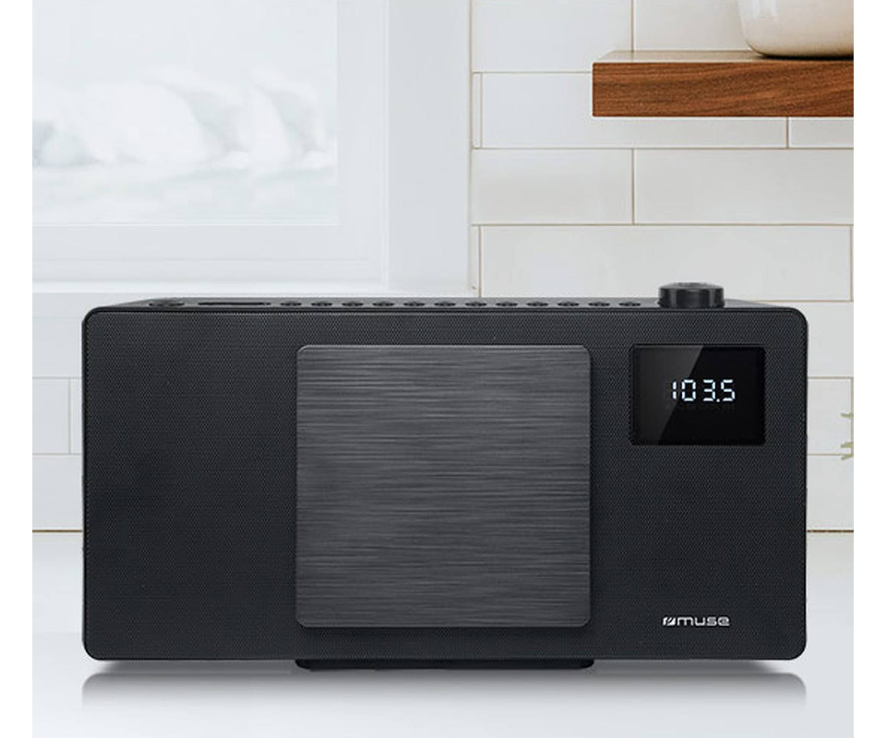 Czarny radio na białym blacie kuchennym. Wyświetla 103,5 na ekranie cyfrowym.