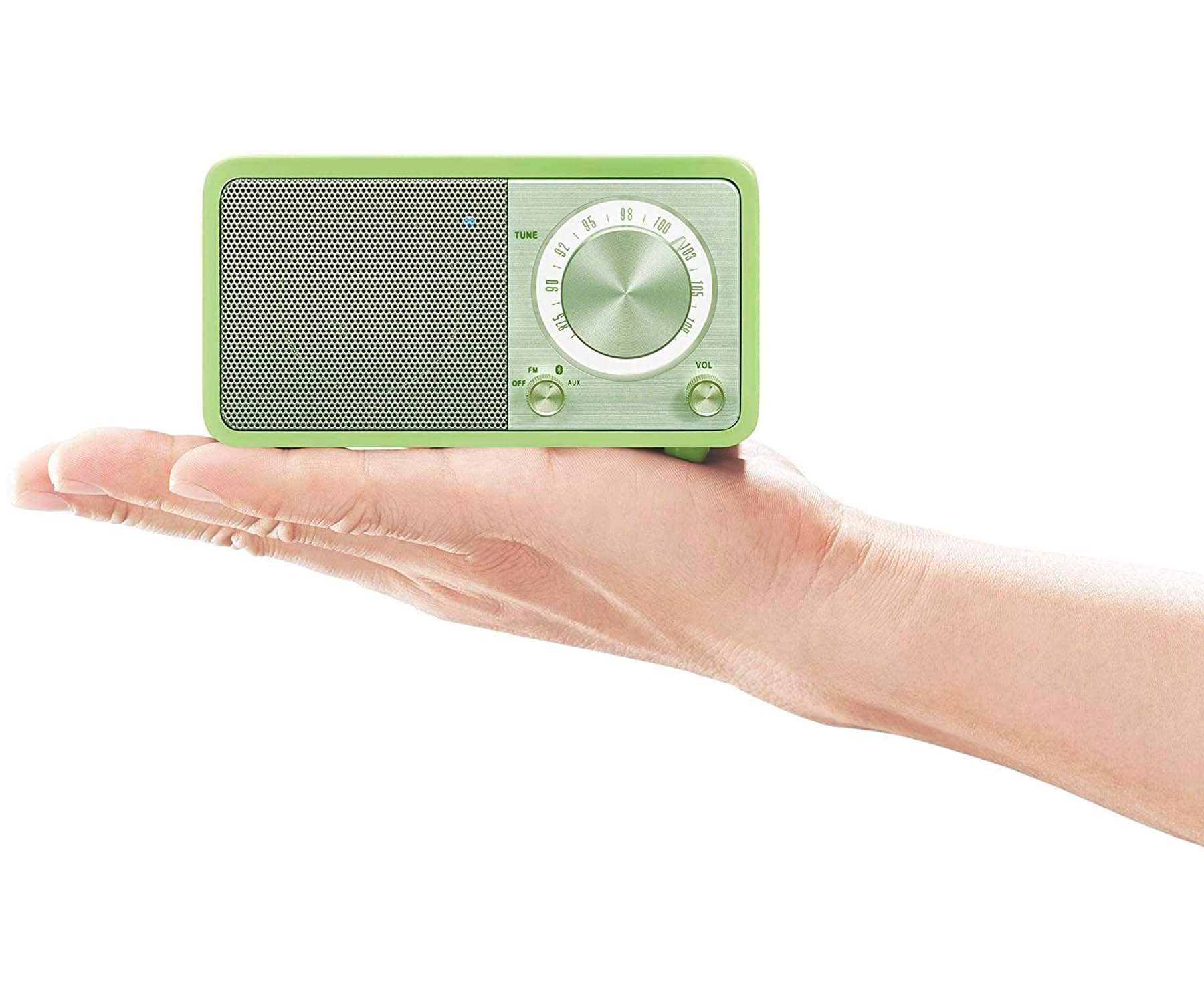 Zielone radio w stylu retro trzymane w dłoni. Ma pokrętło do strojenia i regulacji głośności.