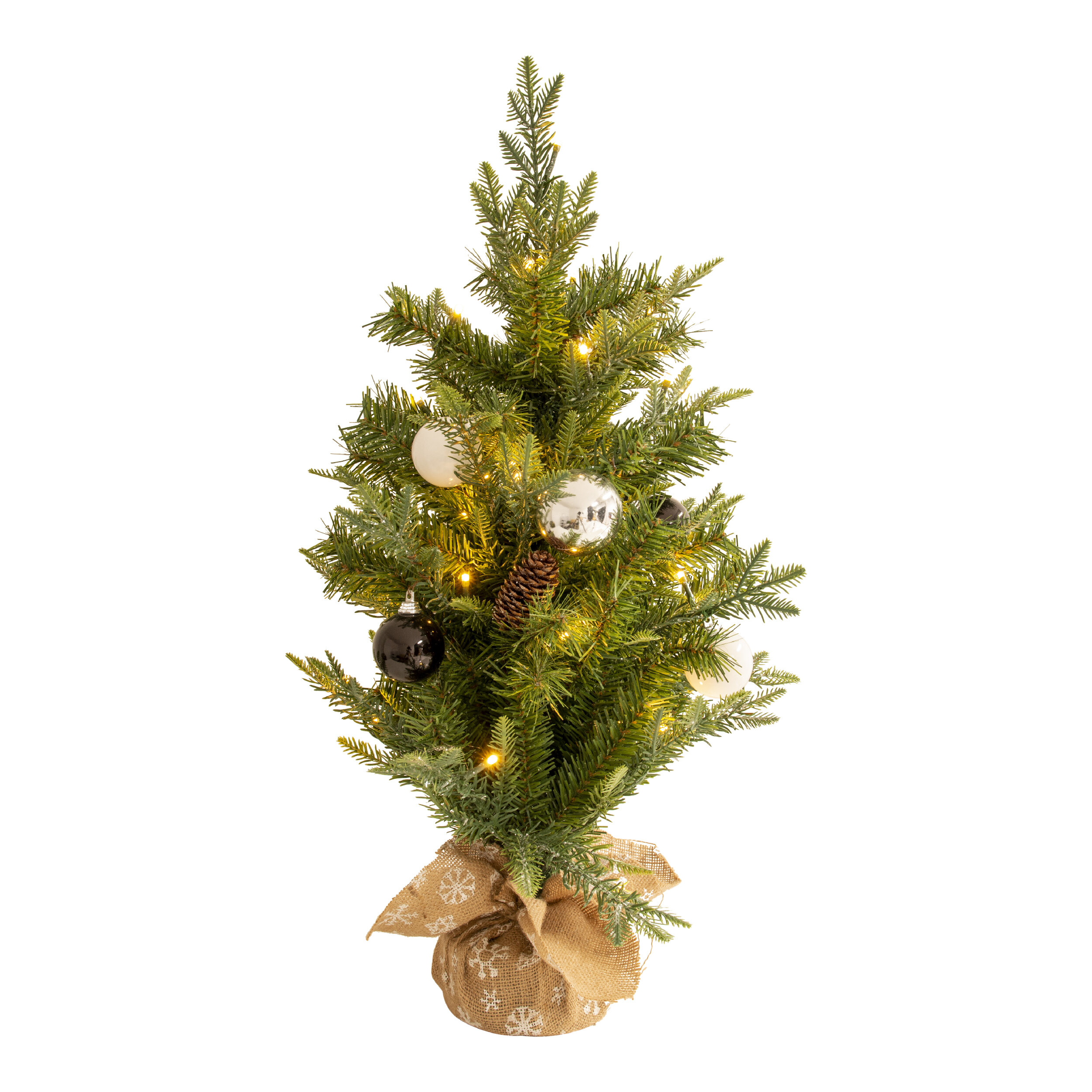 Ein kleiner Weihnachtsbaum mit Ornamenten und Lichtern, in einem Jutesack stehend.