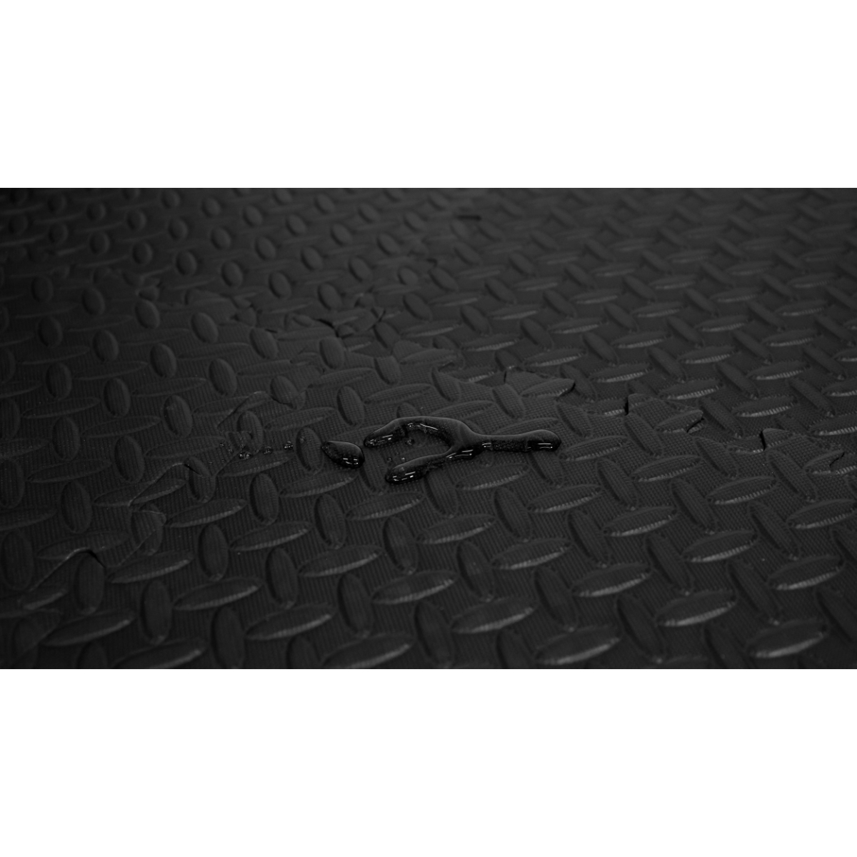 Schwarze Gummimatte mit Wassertropfen. Rautenmuster.
