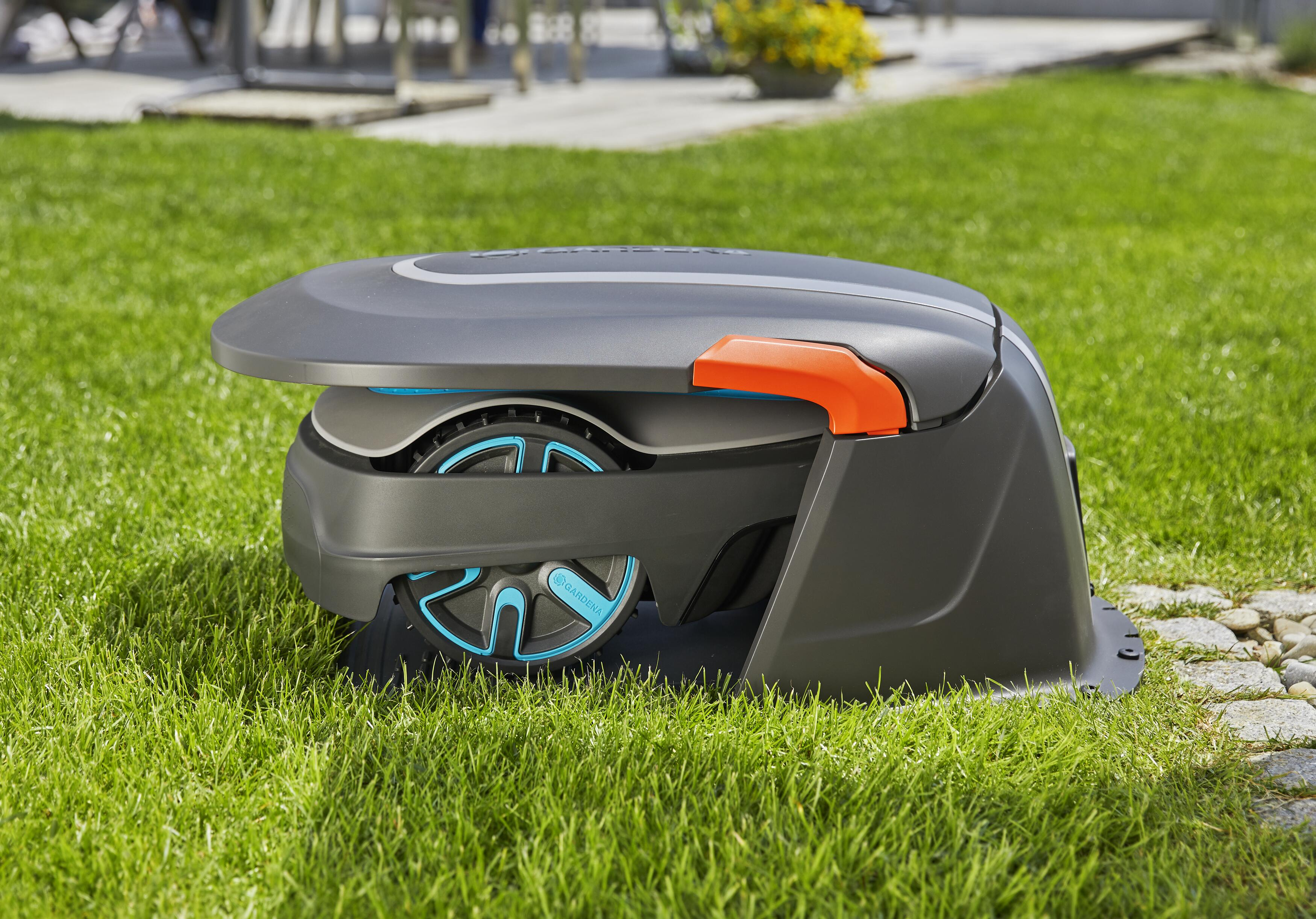 Ein Roboter-Rasenmäher auf grünem Gras mit offenem Deckel und orangefarbenen Akzenten.