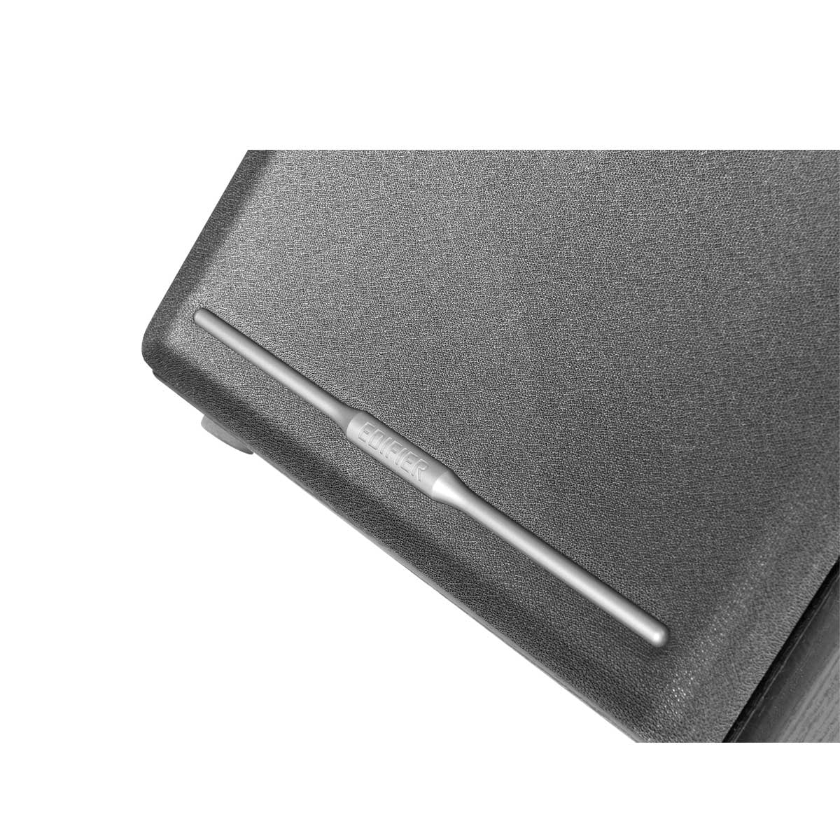 Mały srebrny metalowy pręt z napisem Edifier na ciemnoszarej powierzchni.