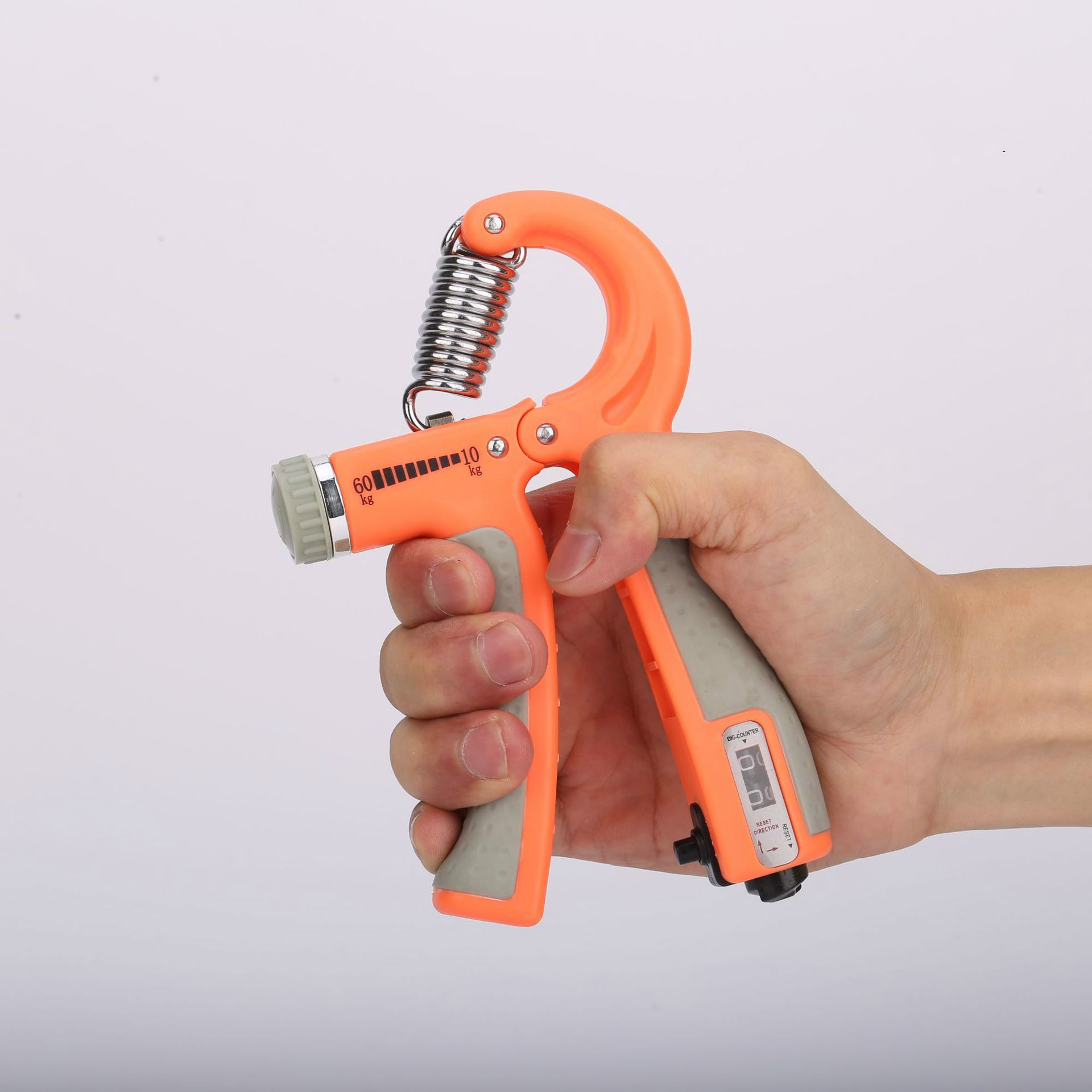 Pomarańczowy uchwyt do ćwiczeń dłoni. Wyświetla ustawienie kg i licznik.