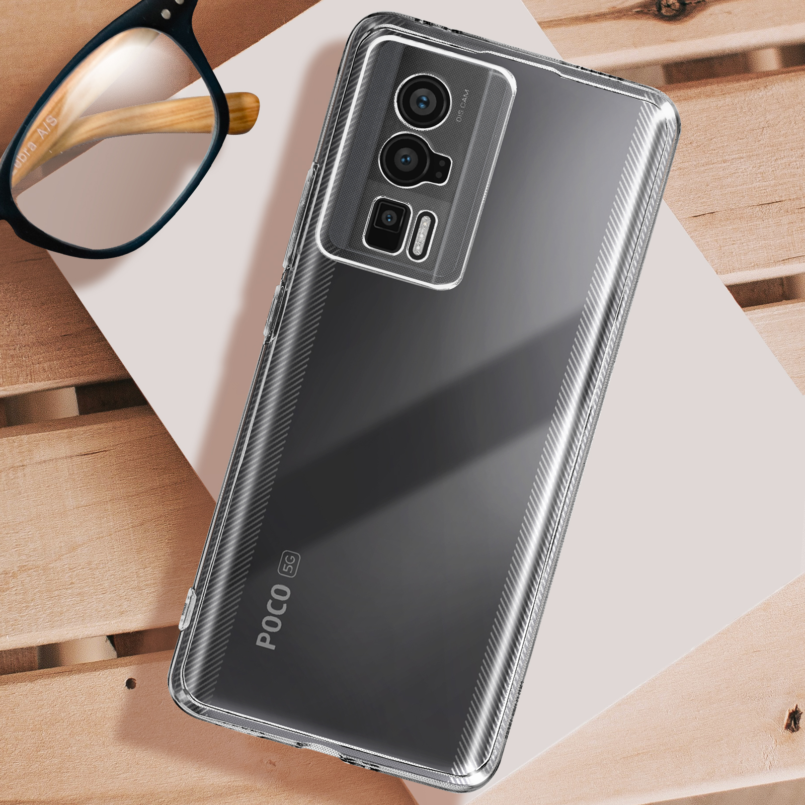 Una custodia trasparente per telefono su una superficie di legno, con un telefono dentro e occhiali sopra.