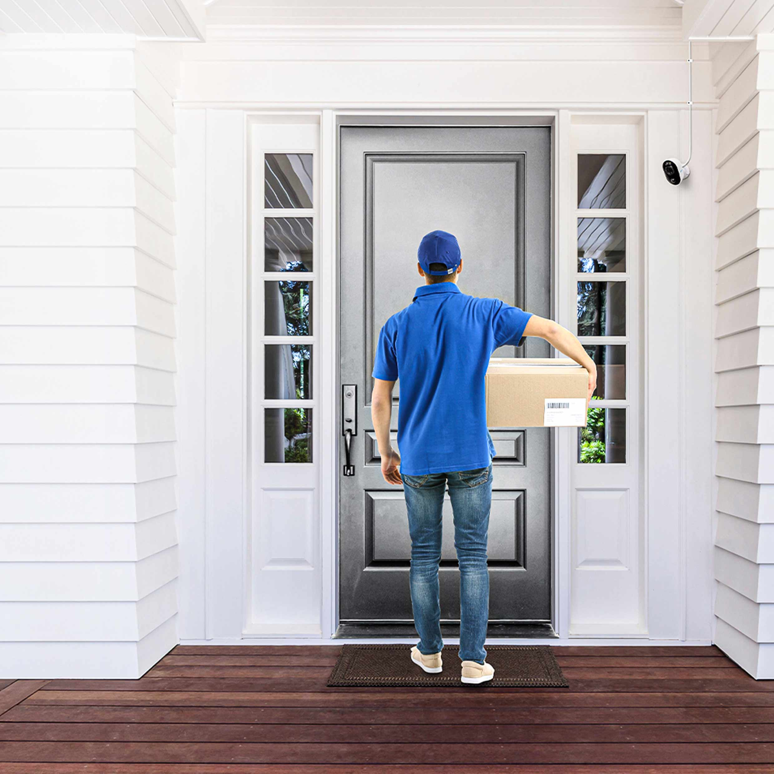 Dostawca z paczką przy białych drzwiach z kamerą bezpieczeństwa.