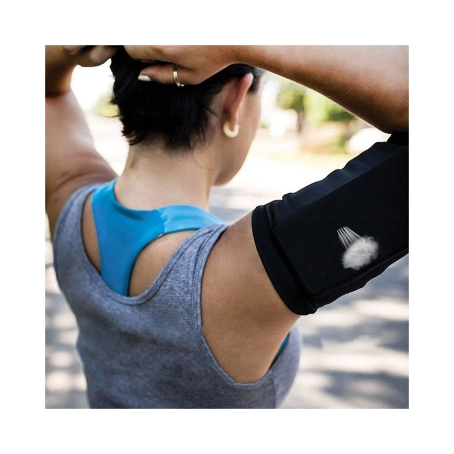 Frau trägt graues Tanktop und blauen Sport-BH, schwarzer Armärmel.