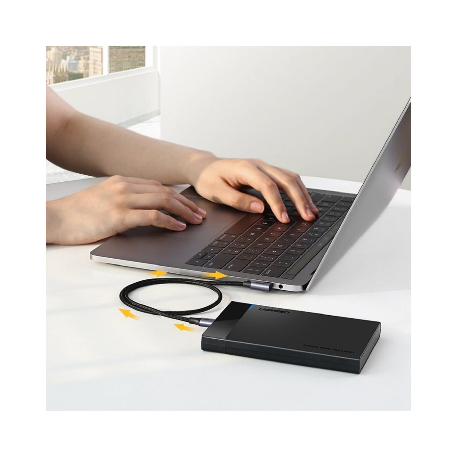 Eine schwarze externe Festplatte, die über ein geflochtenes Kabel mit einem Laptop verbunden ist.