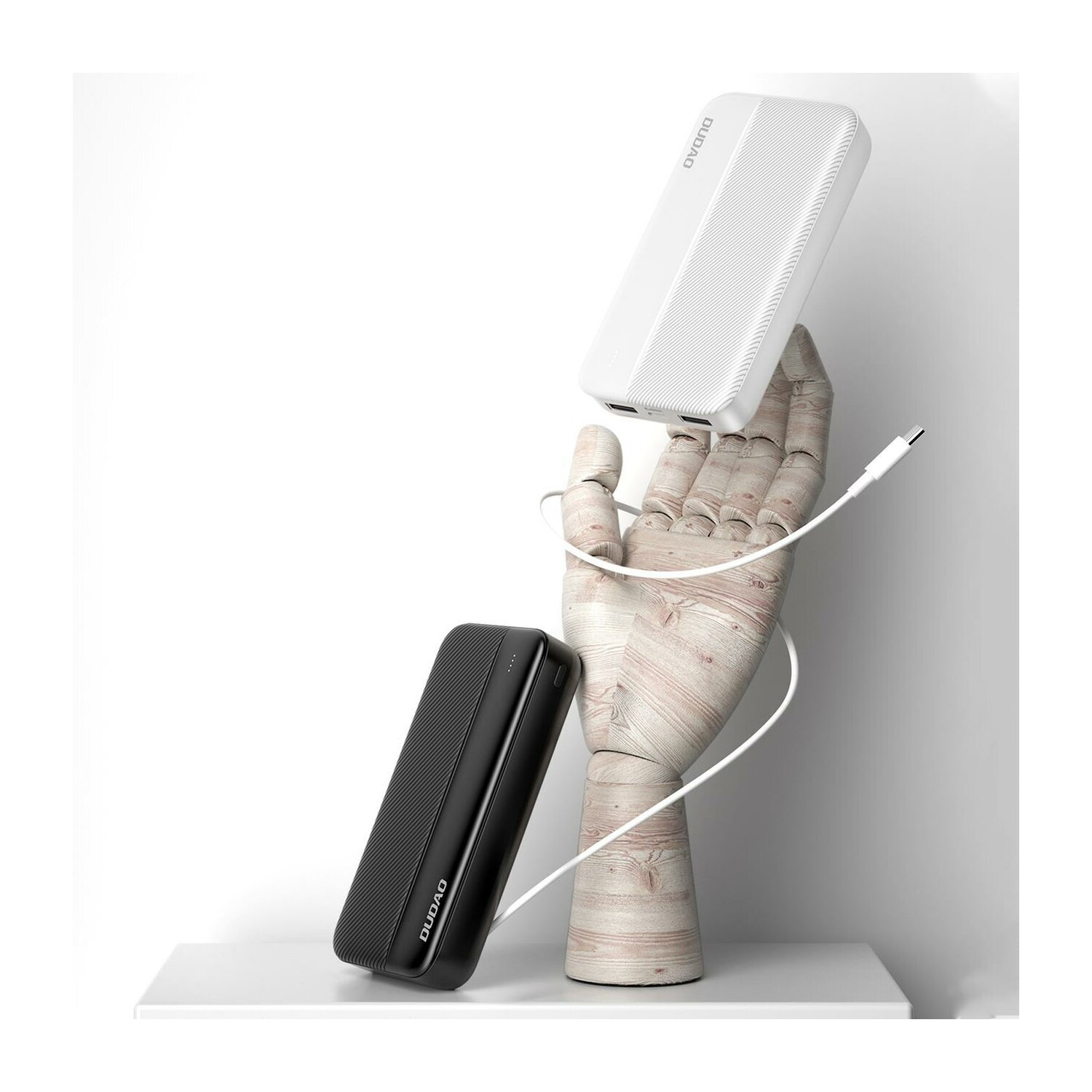 Zwei Powerbanks, eine schwarz, eine weiß, gehalten von einer Holzhand. Weißer Hintergrund.