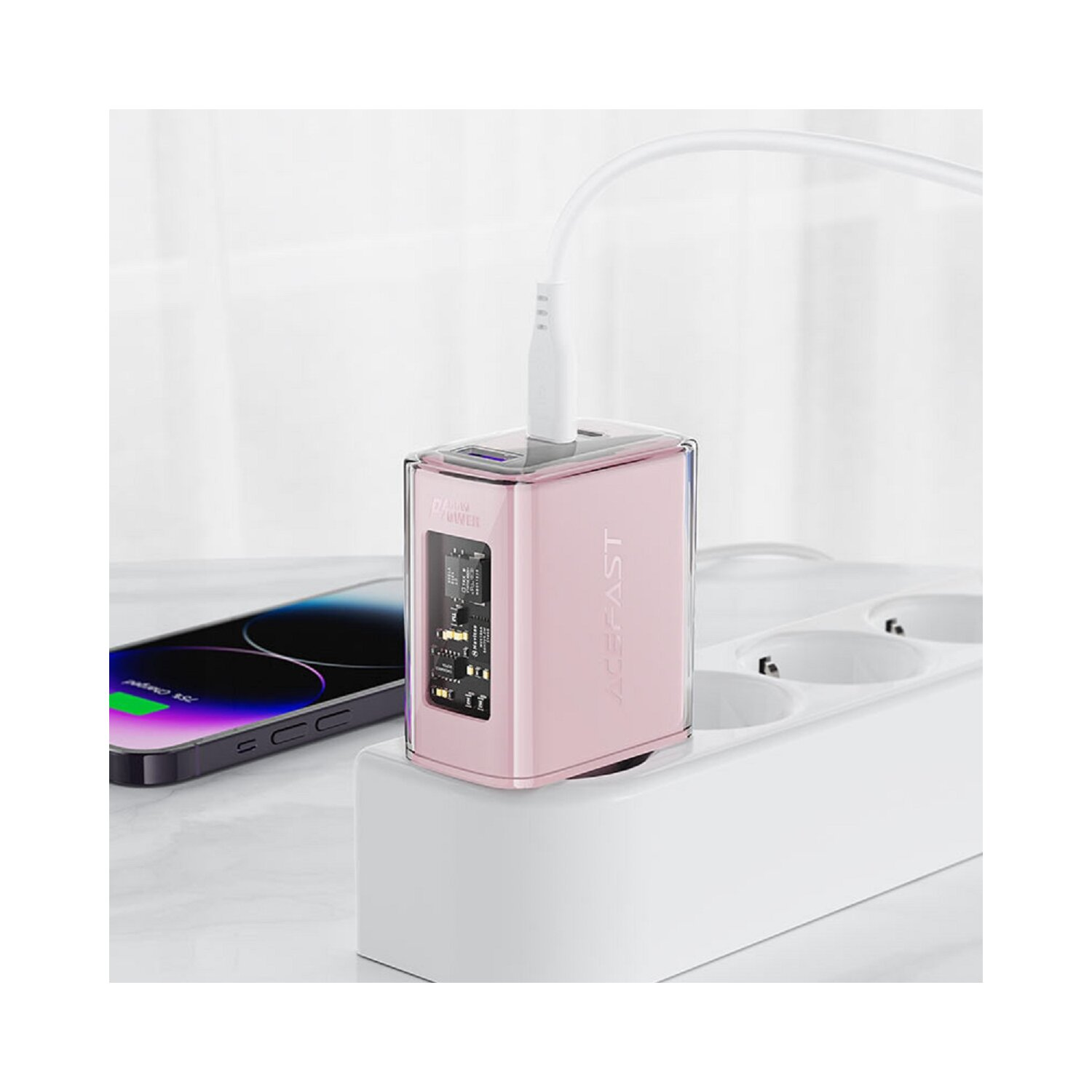 Ein rosa-transparenter Netzadapter, der in eine weiße Steckdosenleiste gesteckt ist, daneben ein Telefon.