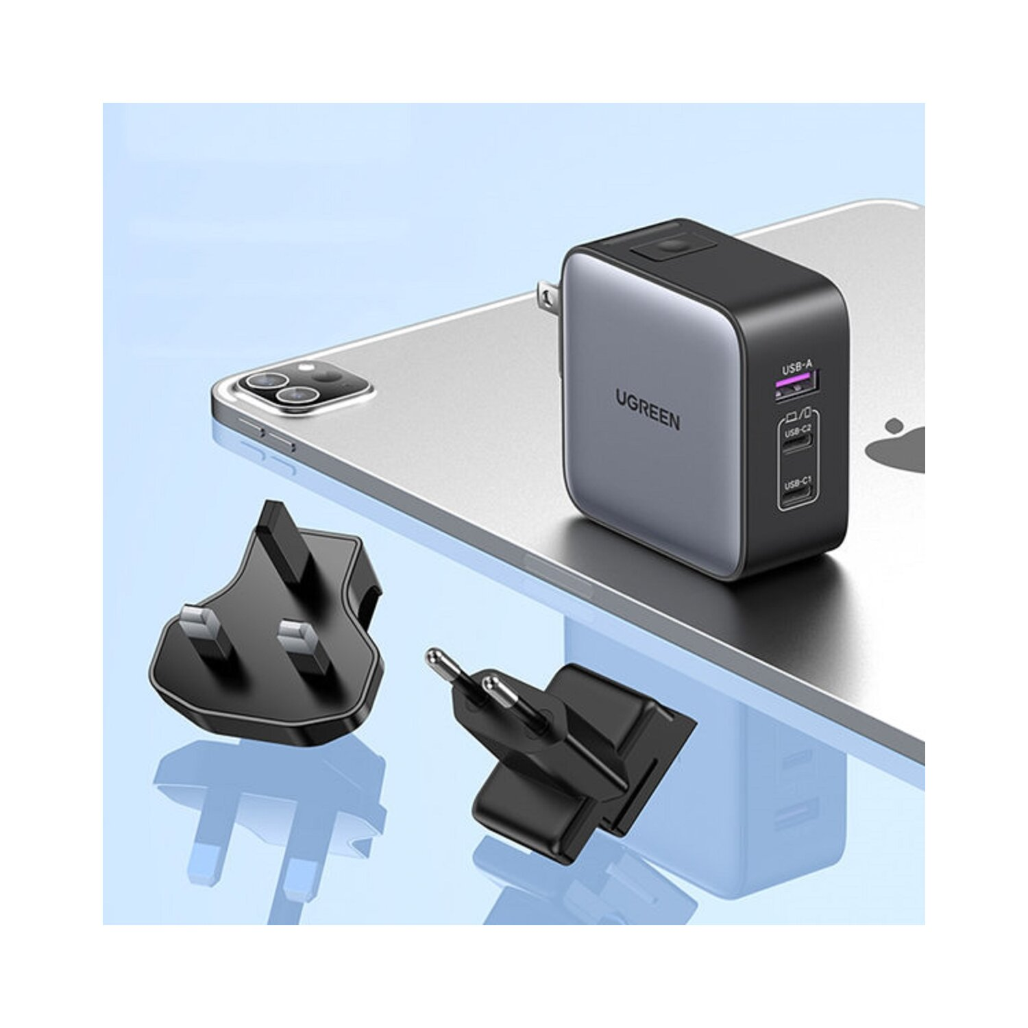 Czarna ładowarka UGREEN z trzema wtyczkami na tablecie. Wtyczki również są czarne.