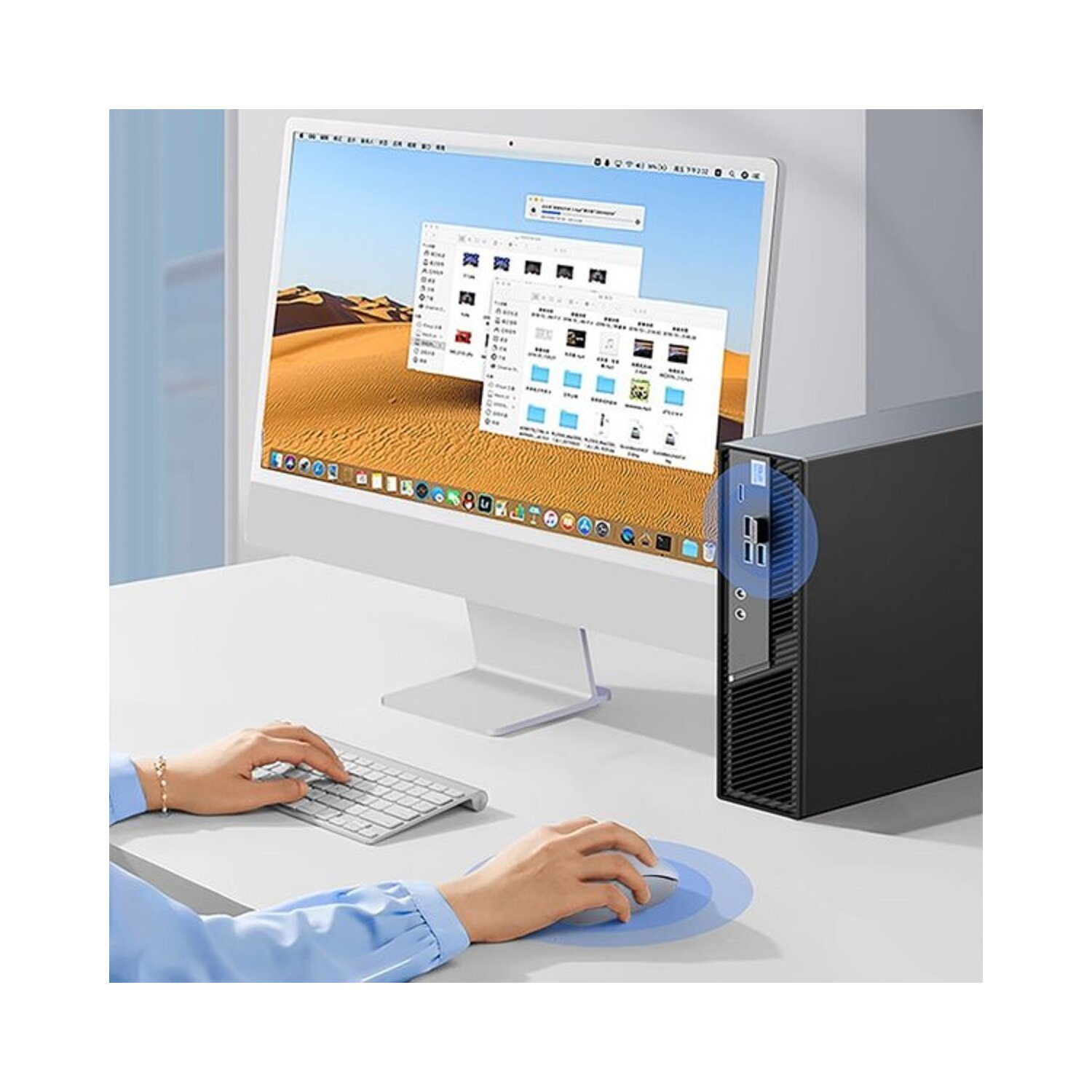 Ręce używające myszy i klawiatury przy biurku z komputerem. Ekran komputera pokazuje wiele ikon.