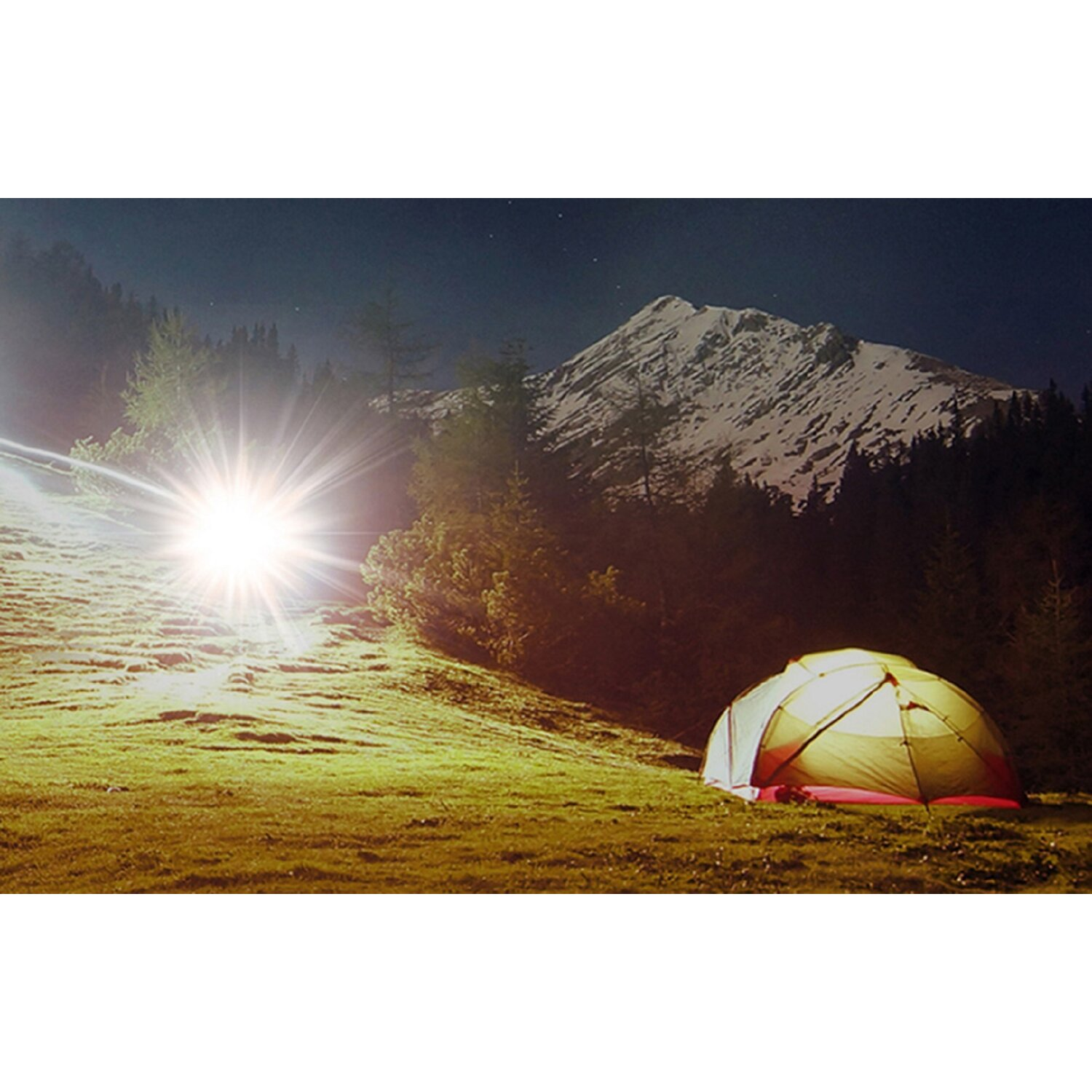 Ein beleuchtetes Zelt auf einem Feld bei Nacht. Helle Licht und Berge im Hintergrund.