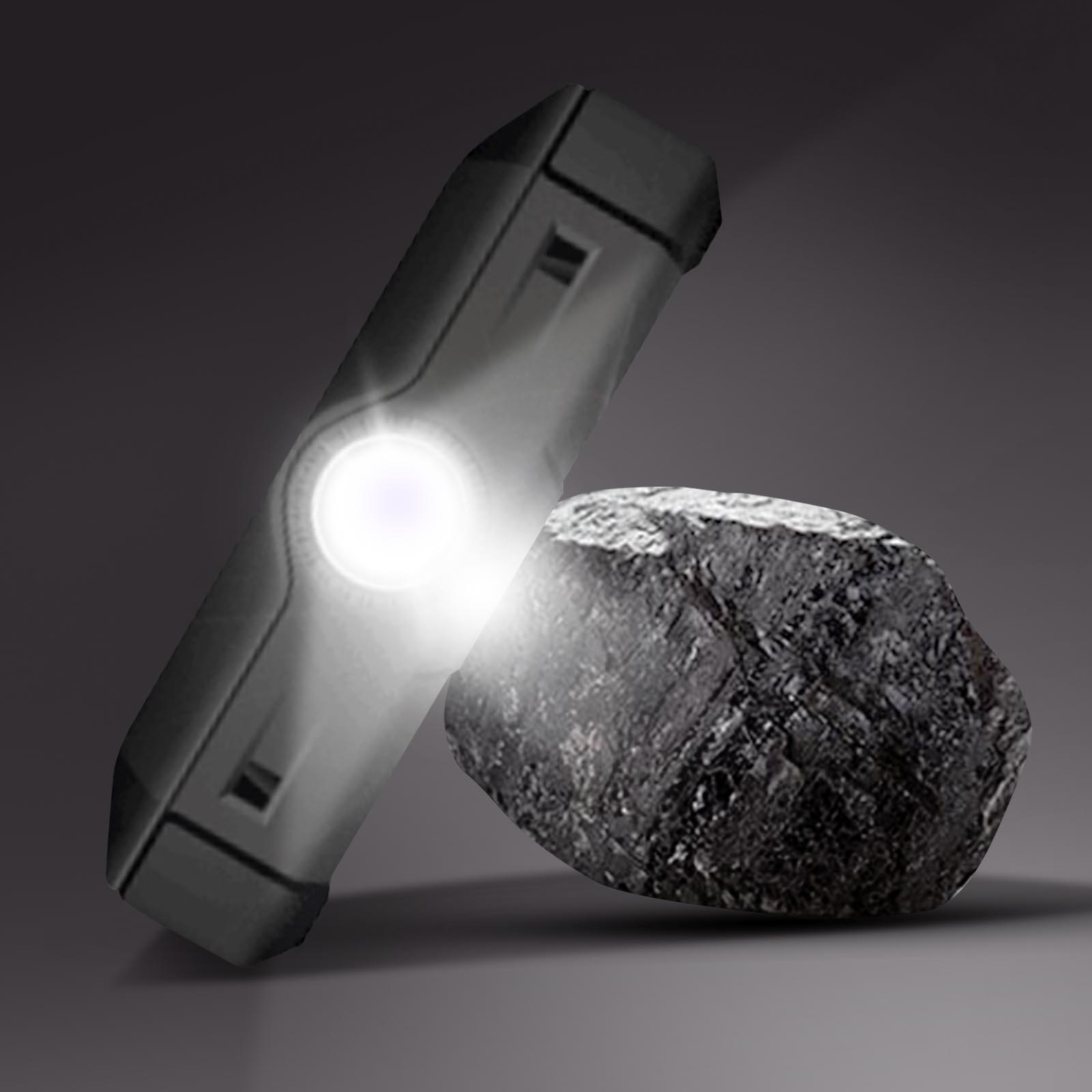Eine Taschenlampe, die auf einen schwarzen Felsen scheint. Die Lichtquelle ist hell. Dunkler Hintergrund.