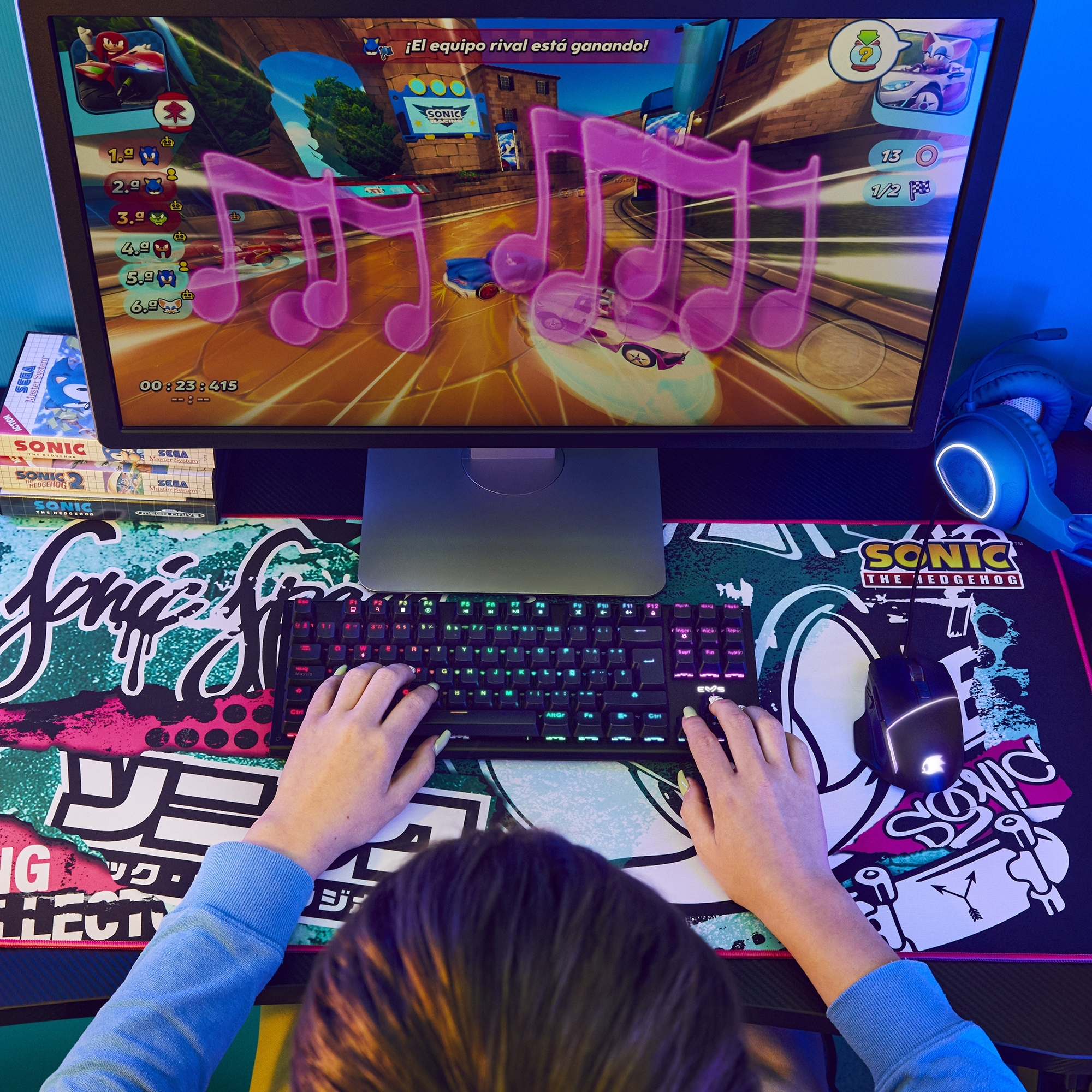 Manos usando un teclado y un ratón, jugando a un juego en un monitor. Tema de juego retro con Sonic.