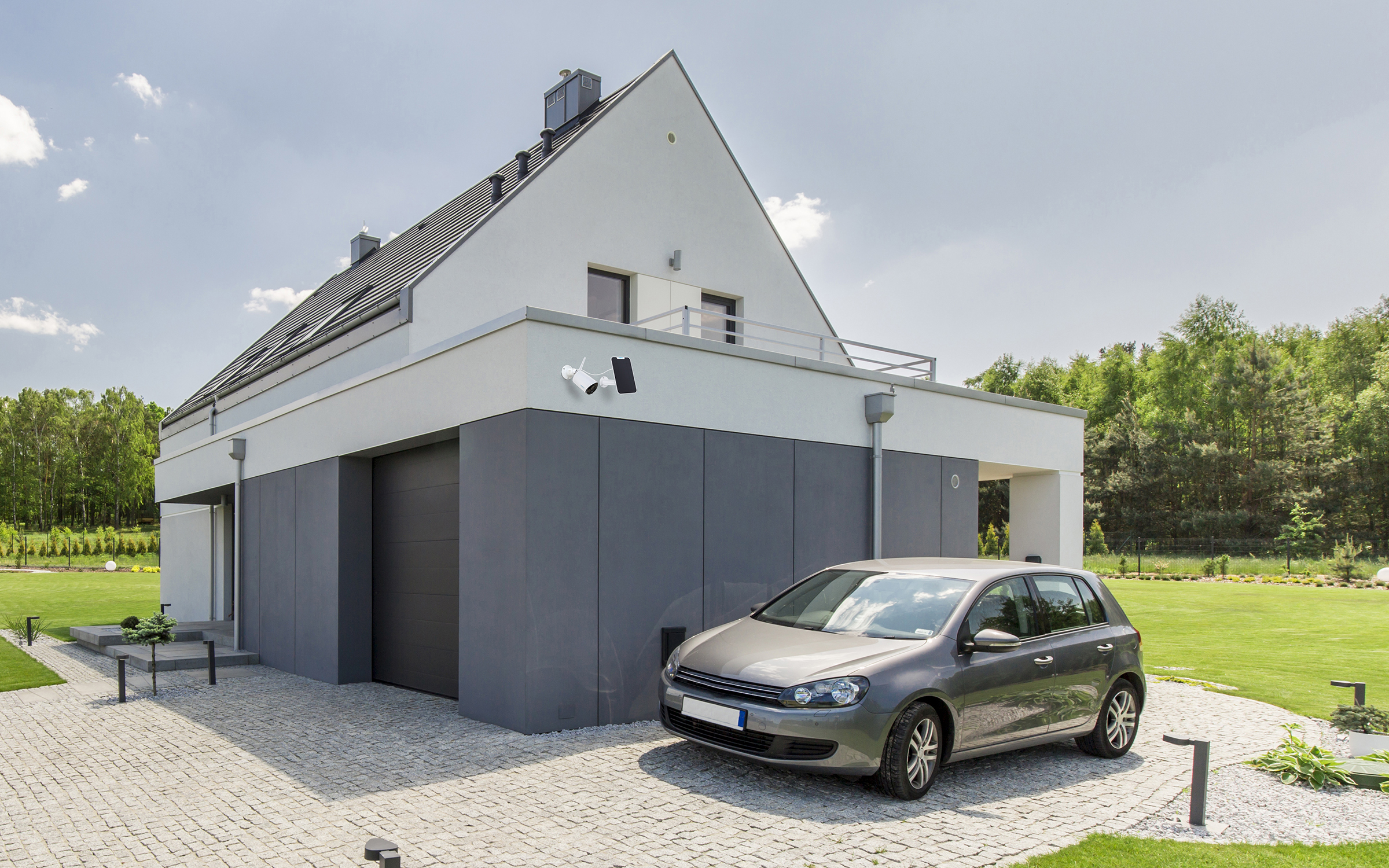 Ein modernes zweistöckiges Haus mit einem grauen Auto auf einer Kopfsteinpflasterauffahrt. Grüner Rasen und Bäume im Hintergrund.