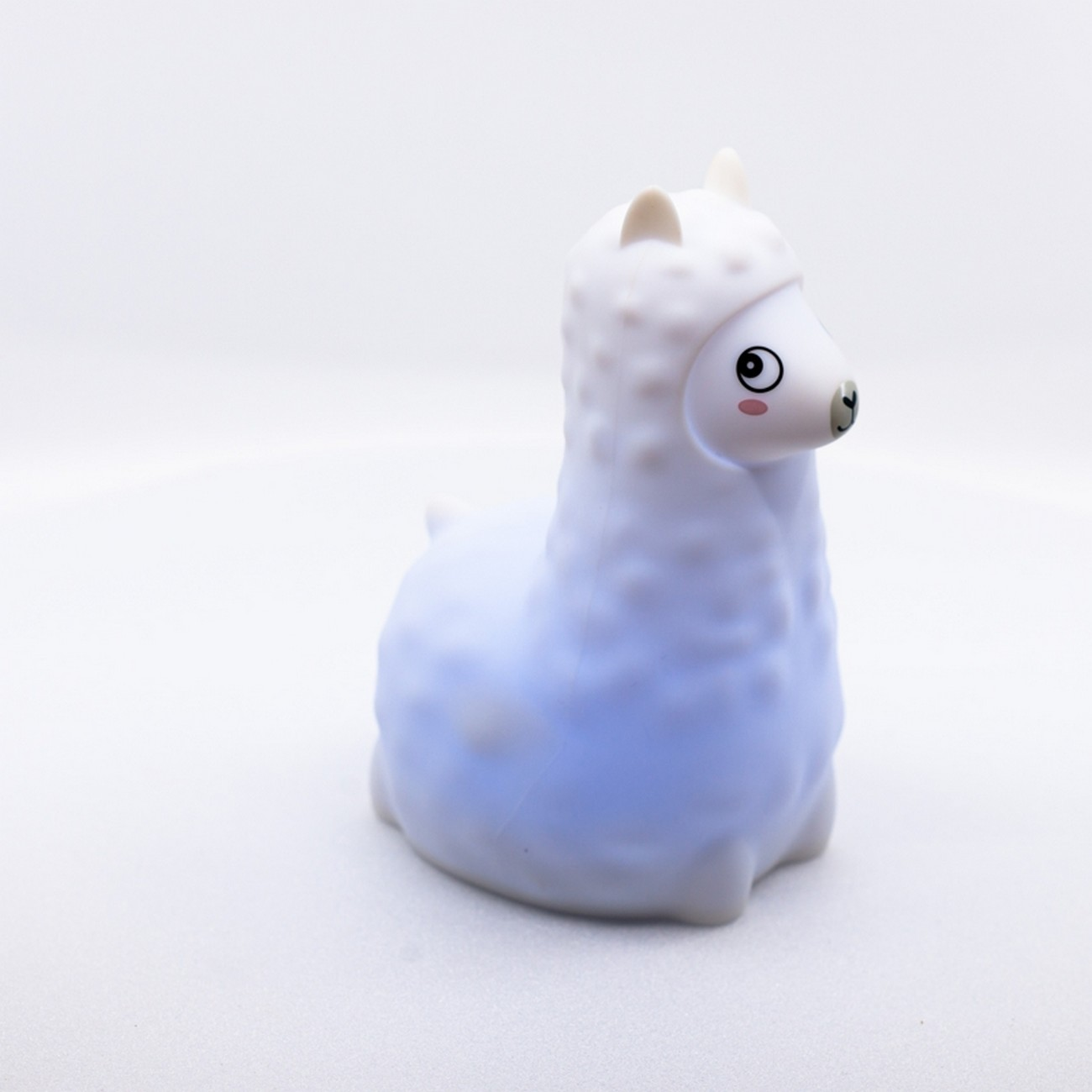 Luz de noche con forma de llama blanca con cuerpo azul y mejillas rosas.