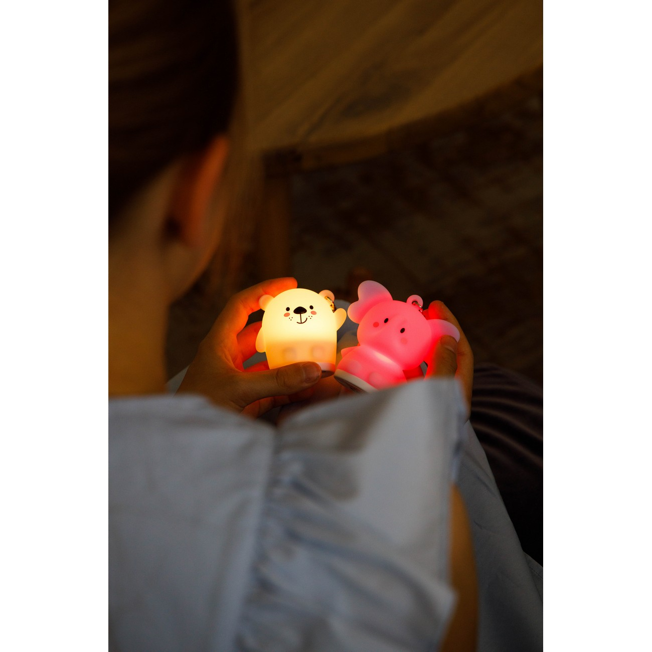 Manos sosteniendo dos juguetes brillantes: un oso y un cerdo. Los juguetes son rosas y amarillos.