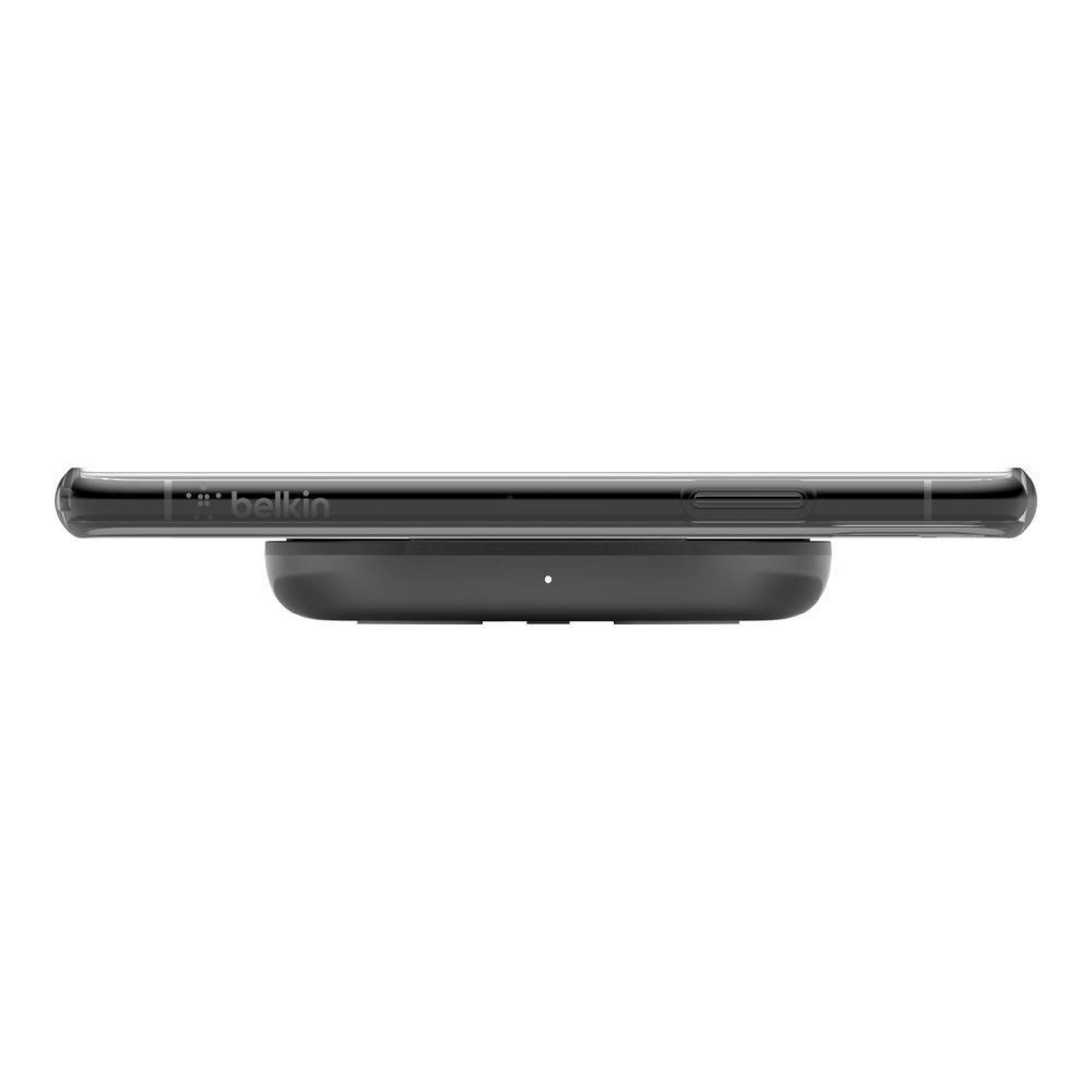 Ein schwarzes Telefon auf einem kabellosen Ladepad, mit dem Belkin-Markenlogo, vor weißem Hintergrund.