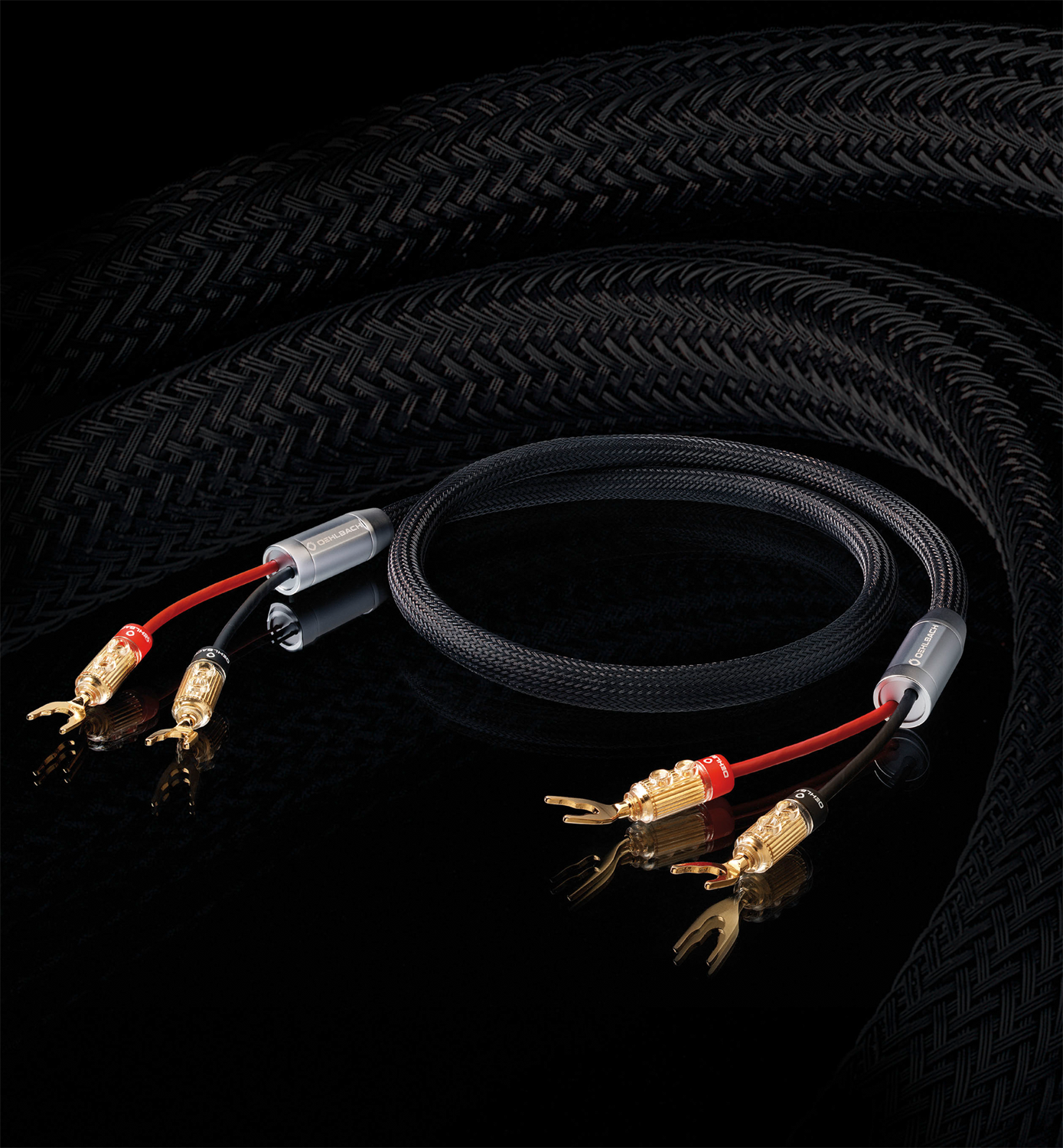 Schwarze Audiokabel mit roten und goldenen Steckern auf einer reflektierenden schwarzen Oberfläche.