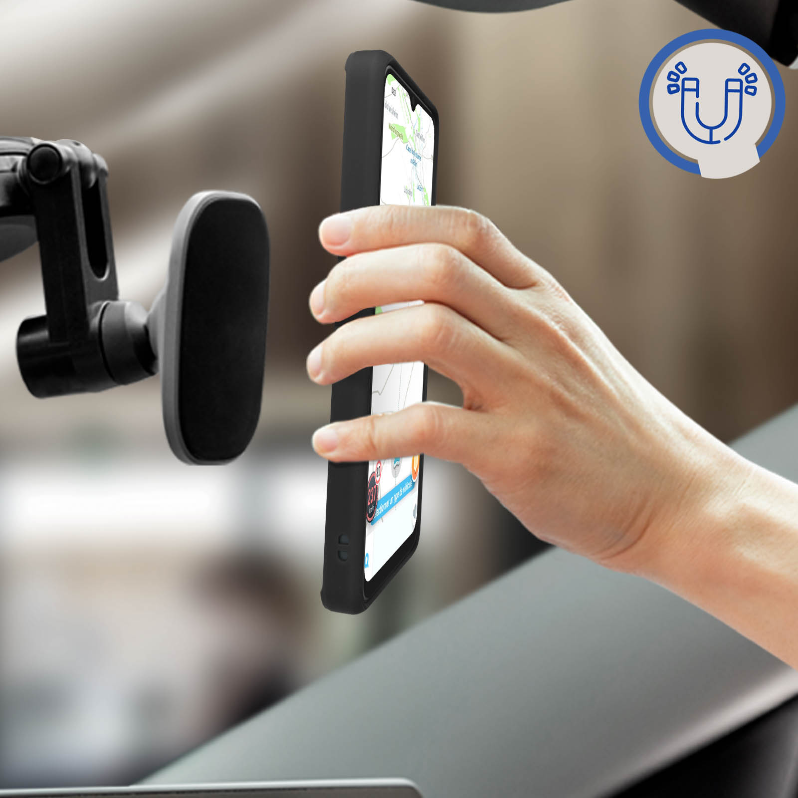 Mano che tiene un telefono in auto, vicino a un supporto magnetico. Interni dell'auto visibili.