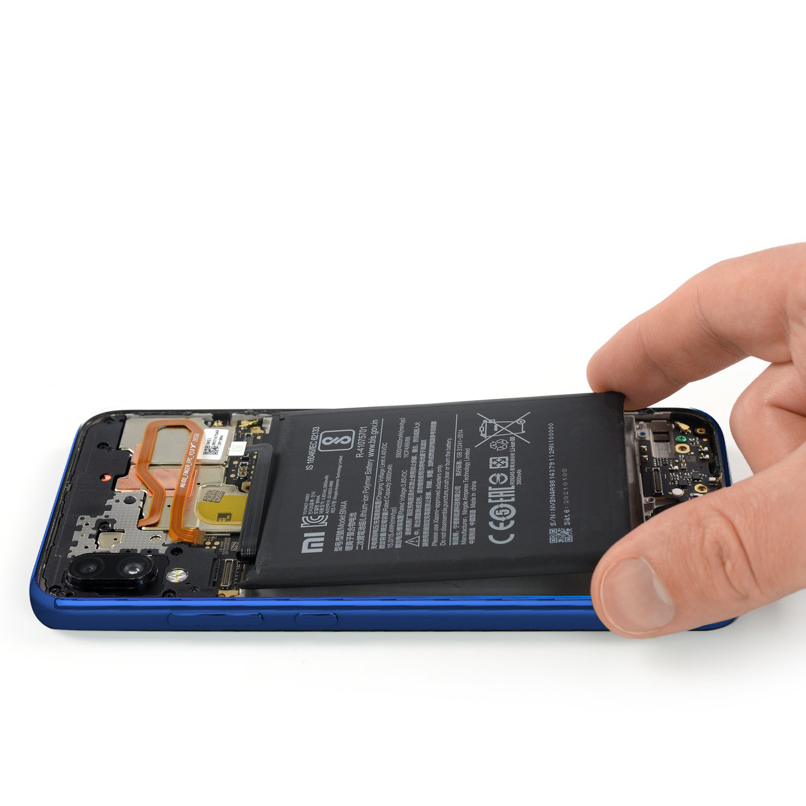 Eine Hand, die einen Akku aus einem blauen Handy entfernt, wobei die internen Komponenten sichtbar sind.