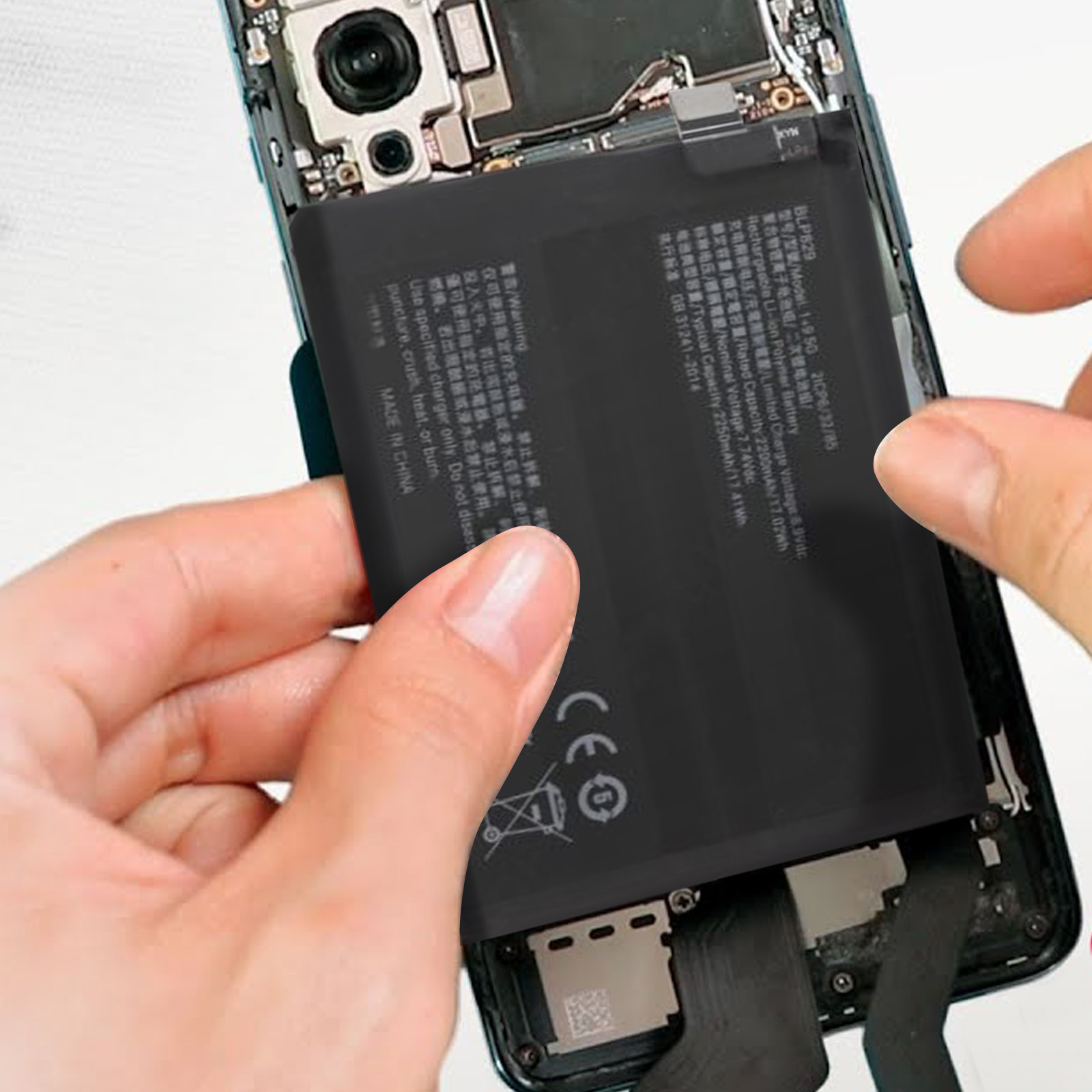 Hände halten einen schwarzen Akku. Das Innere eines Telefons ist sichtbar. Text und Warnungen sind auf der Batterie gedruckt.