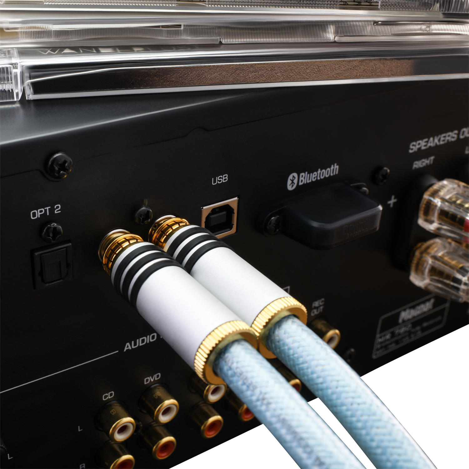Nahaufnahme von Audiokabeln, die in die Rückseite eines schwarzen Verstärkers eingesteckt sind, mit USB- und Bluetooth-Anschlüssen.