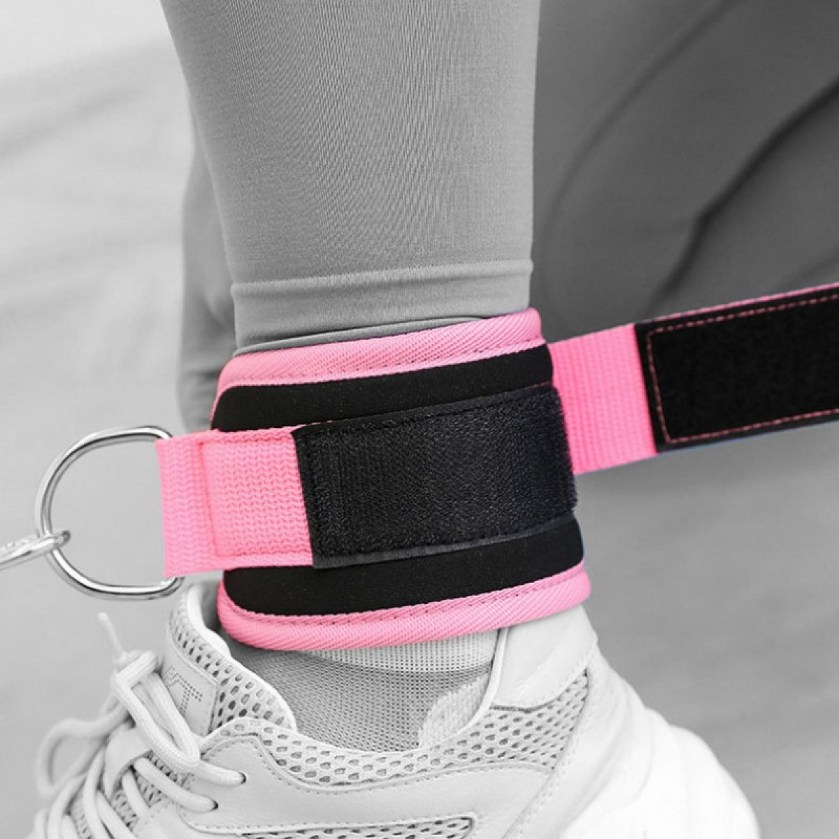 Nahaufnahme eines Fußes mit rosa Knöchelriemen, die an einem Kabel befestigt sind.