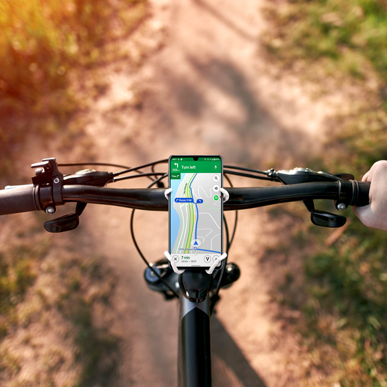 Un telefono sul manubrio di una bici mostra un'app di navigazione su uno sterrato. Il davanti della bici è visibile.