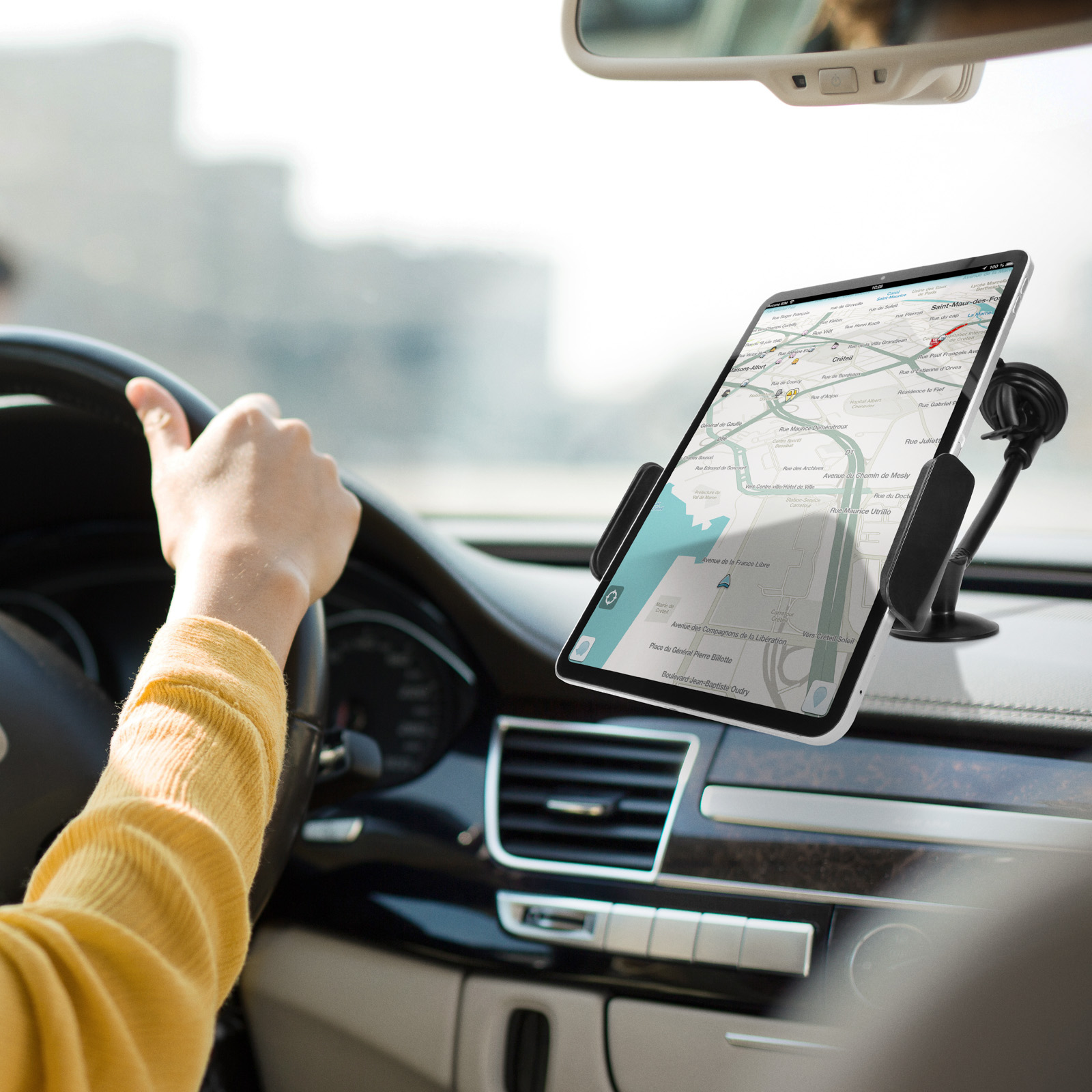 Ein Tablet mit Karte in einer Autohalterung. Die Hand einer Person ist am Lenkrad.