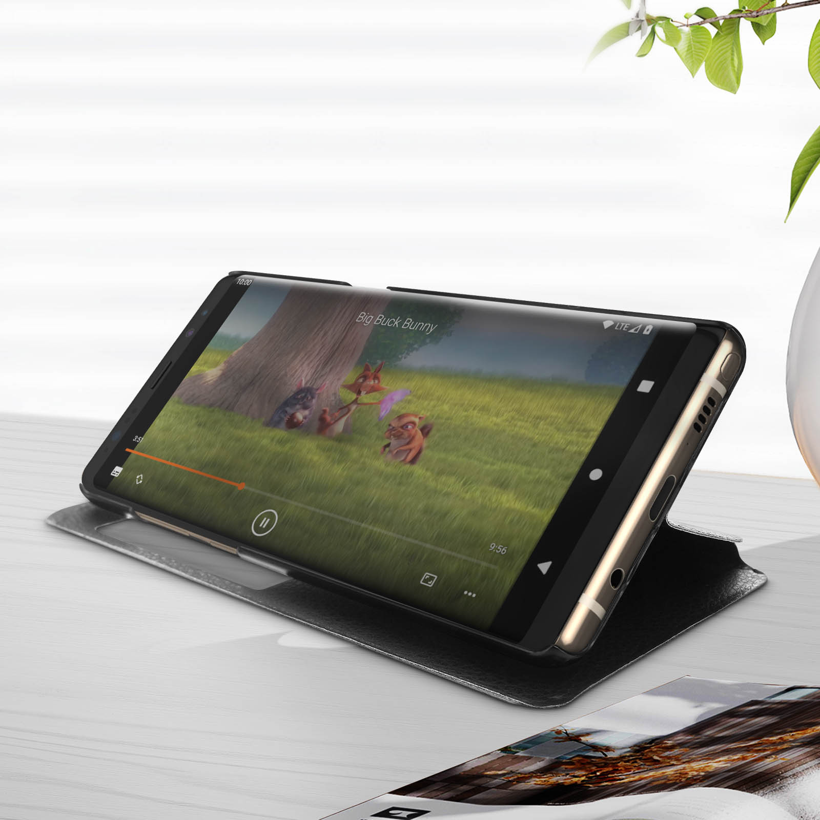 Un smartphone affichant un dessin animé sur une table. Il est dans un étui noir.