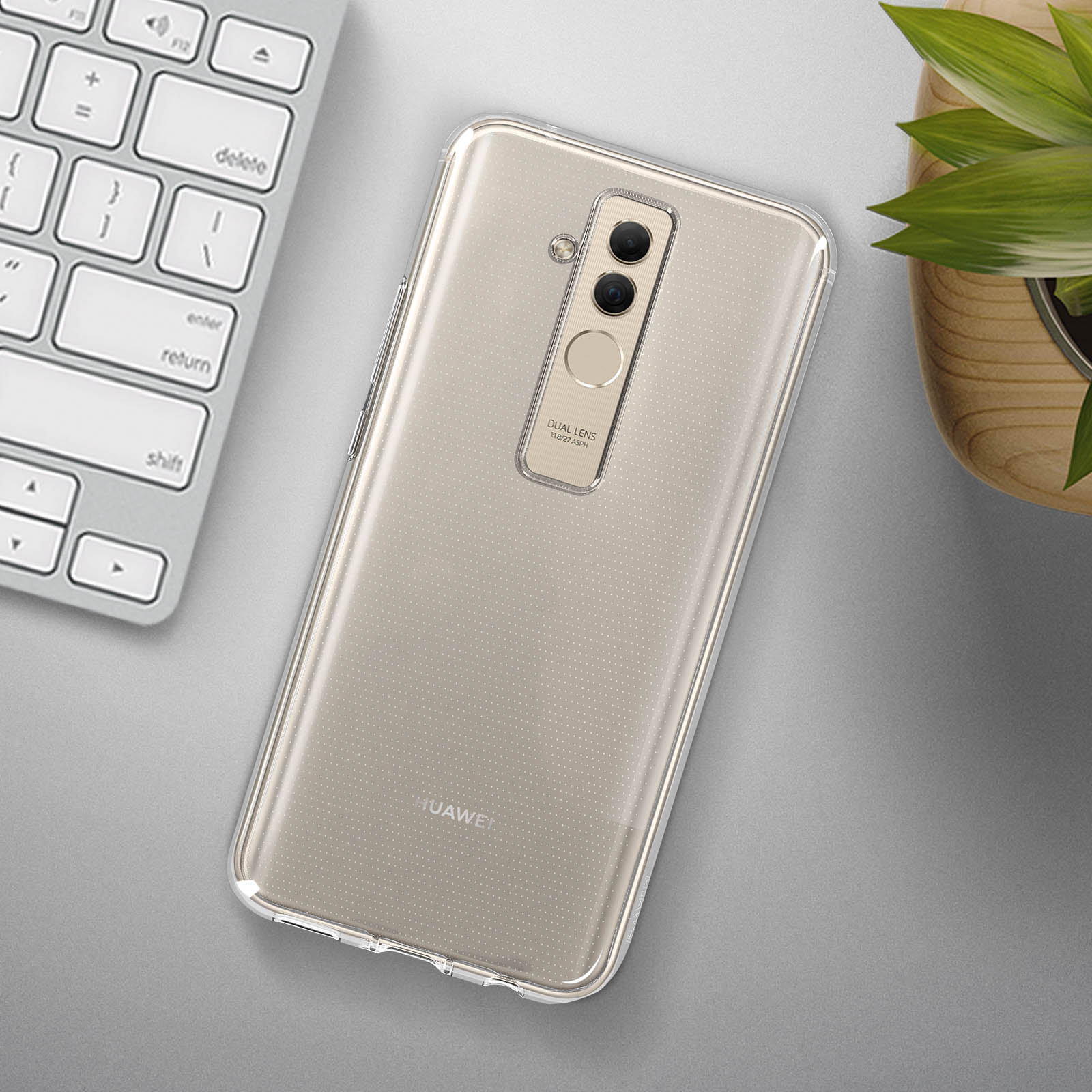 Ein Telefon in einer transparenten Hülle auf einer grauen Oberfläche, mit Tastatur und Pflanze im Hintergrund.