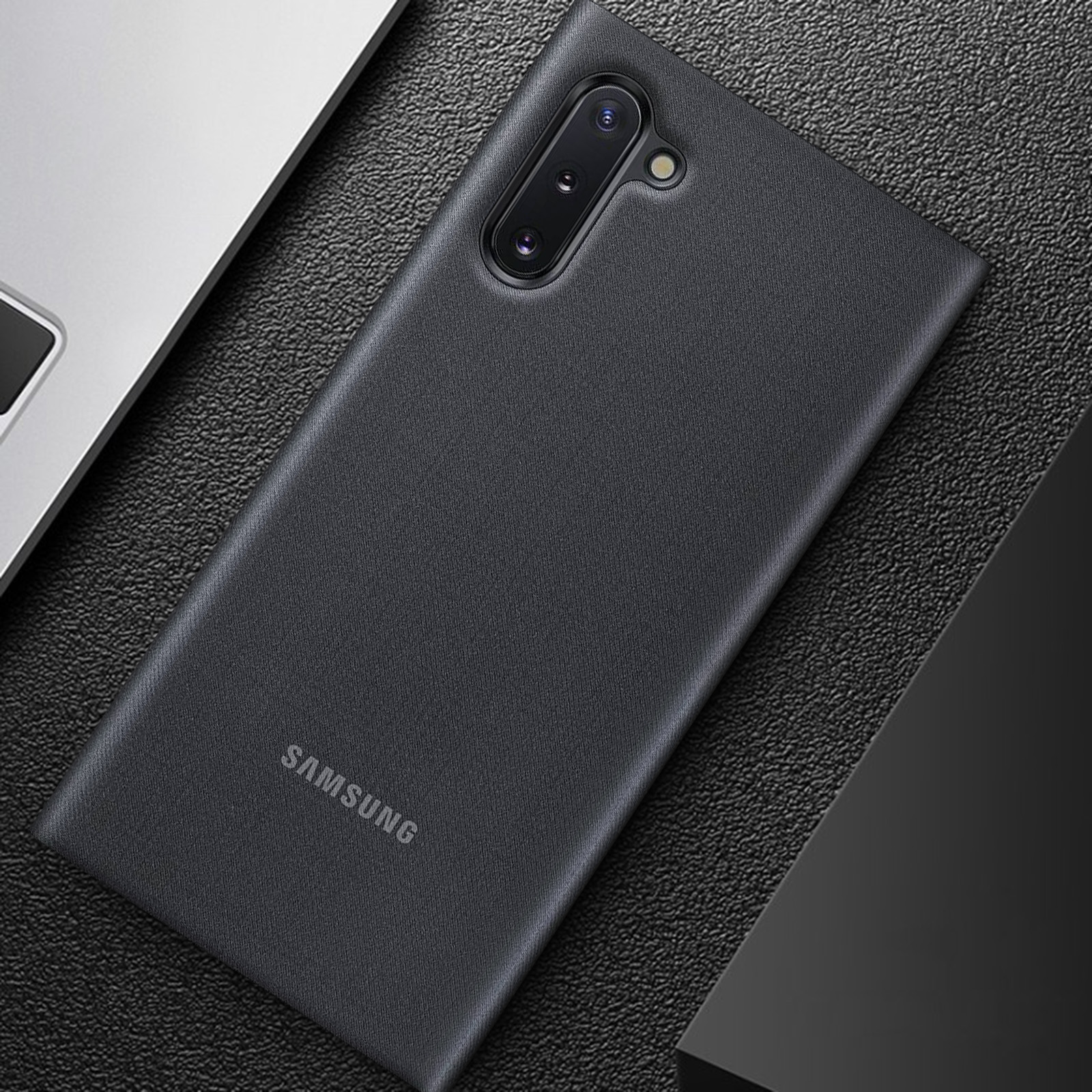 Una custodia nera, con il logo Samsung, su una superficie scura. La custodia ha una trama scura e liscia.