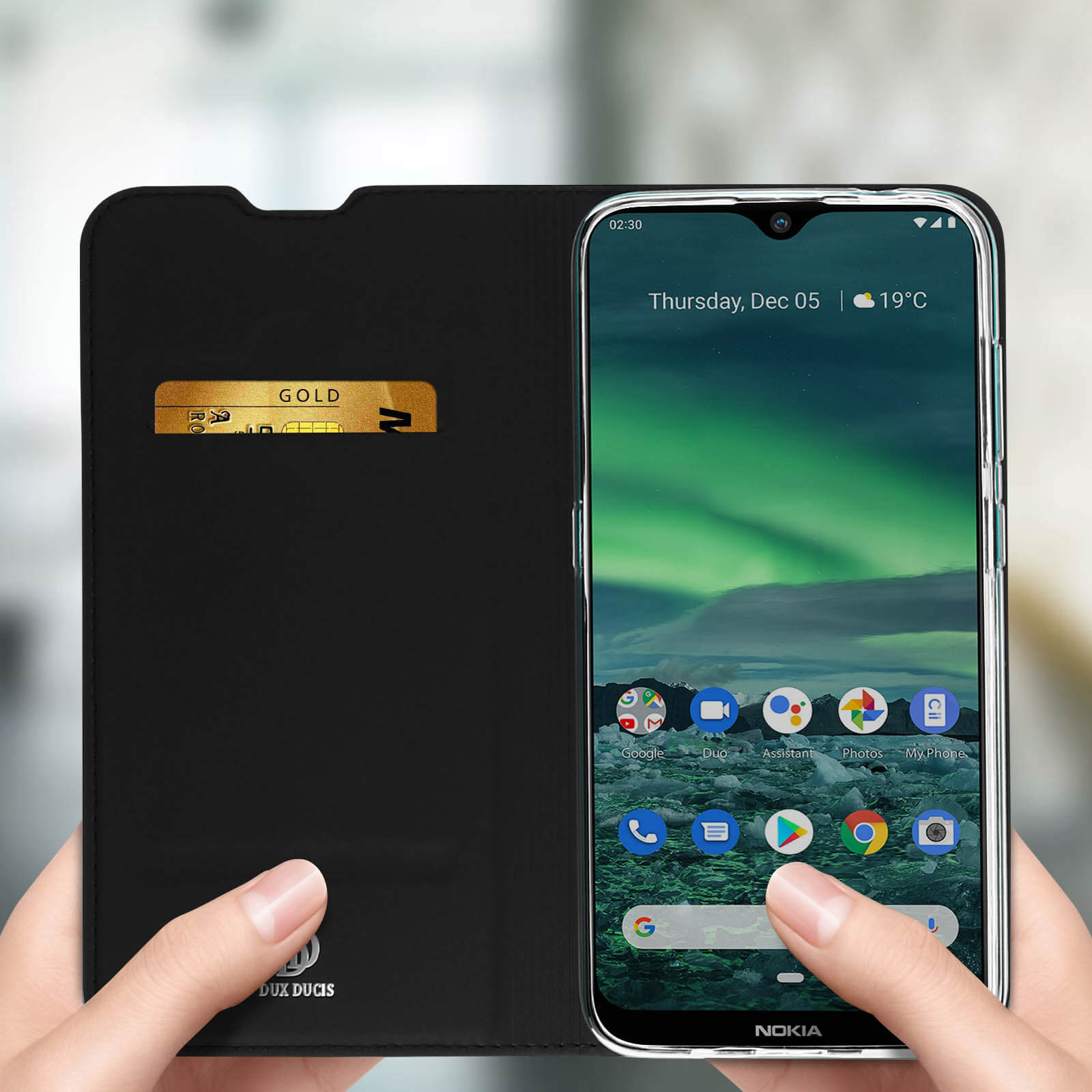 Una custodia nera per telefono con una carta d'oro al suo interno, tenuta da mani, mostrando uno schermo.