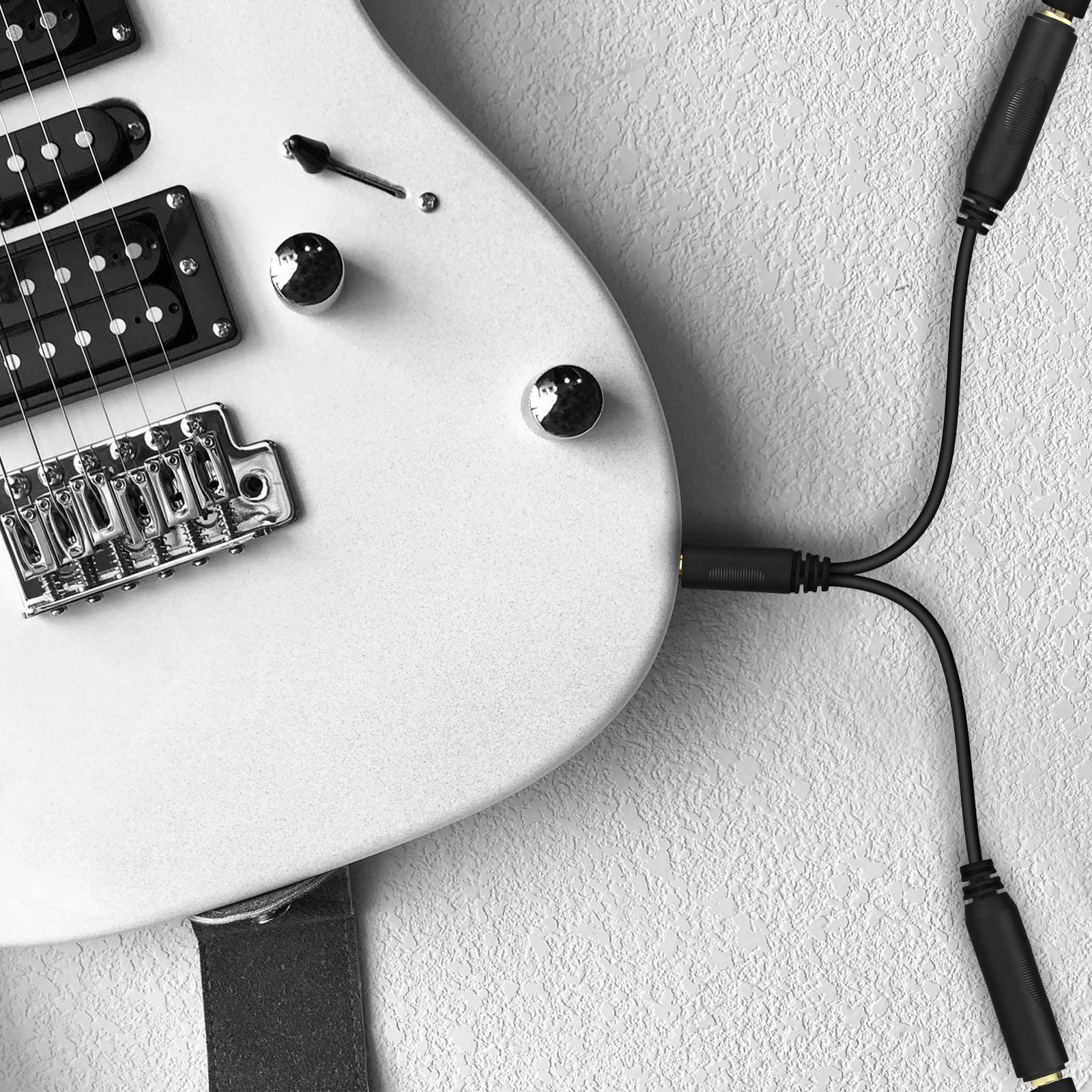 Chitarra elettrica bianca, con pickup neri e cavo nero collegato alla chitarra.