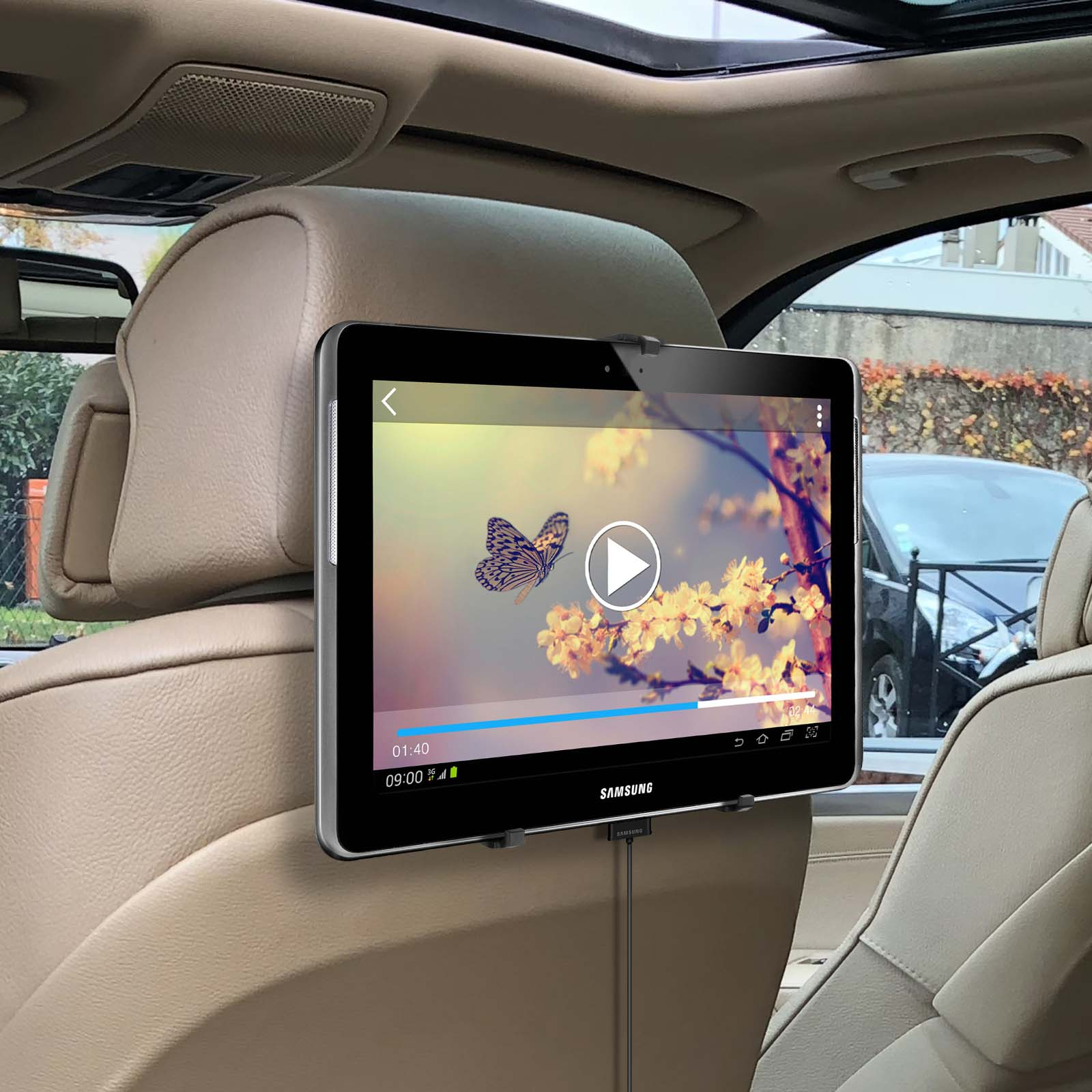 Tablet an Kopfstütze montiert, Video abspielend. Zeigt einen Schmetterling. Beige Autositz im Hintergrund.