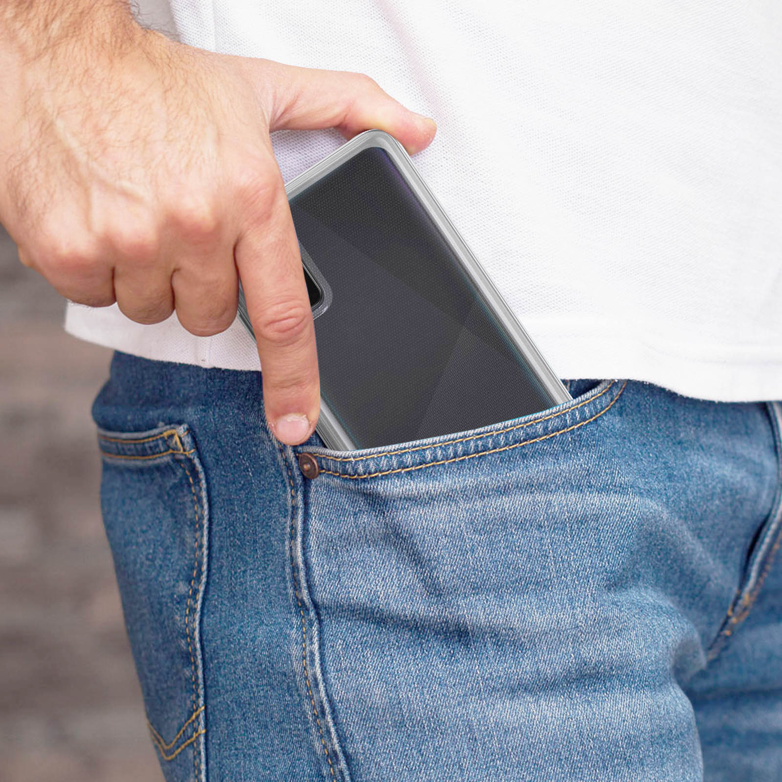Una mano metiendo un teléfono en un bolsillo de jean. El teléfono tiene una funda clara.