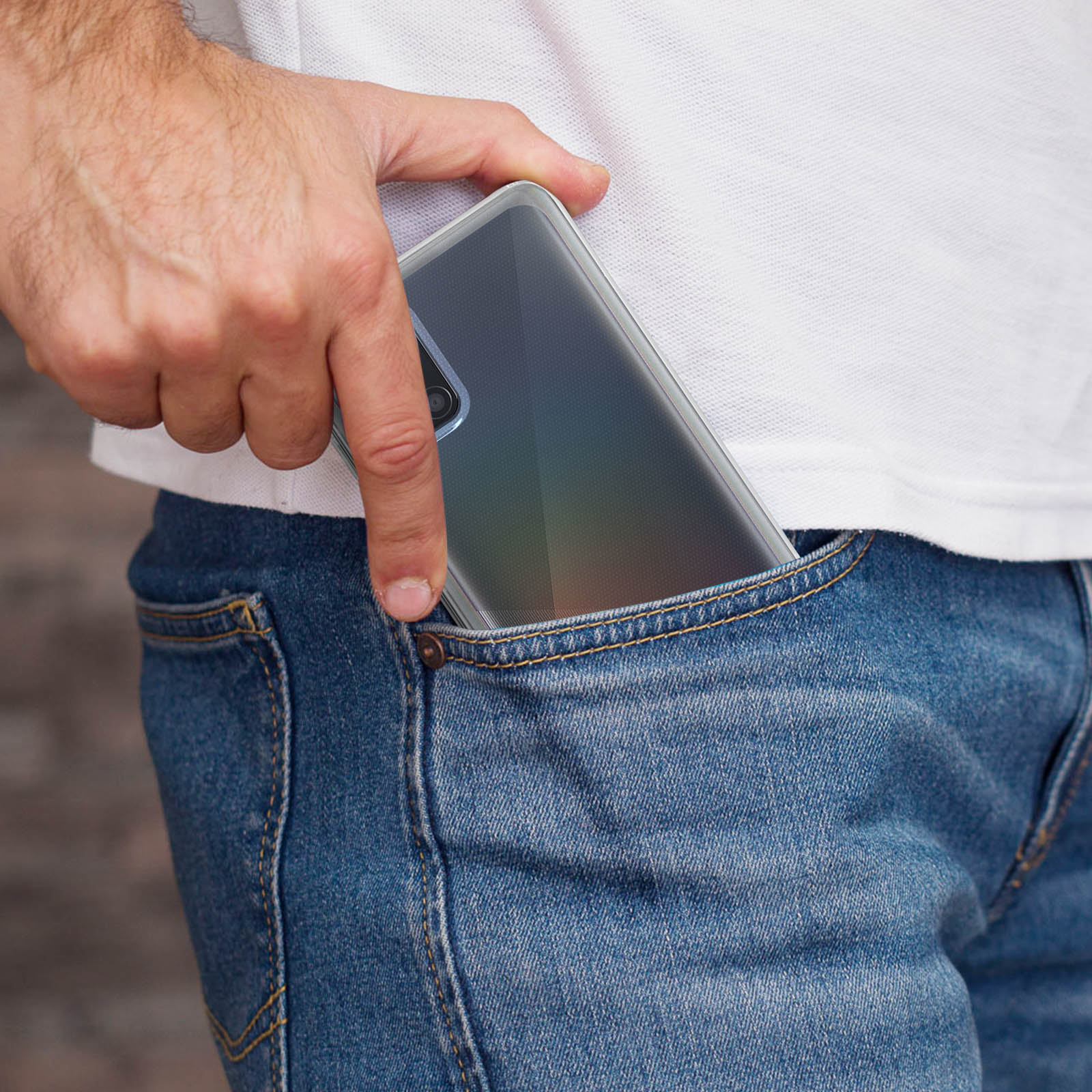 Un telefono in una custodia trasparente in una tasca di jeans. La mano è visibile. Si indossano jeans blu.