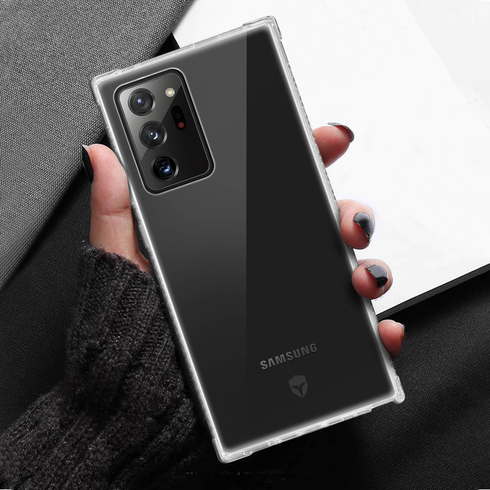 Una custodia trasparente con un telefono dentro, tenuta in mano, su sfondo nero.