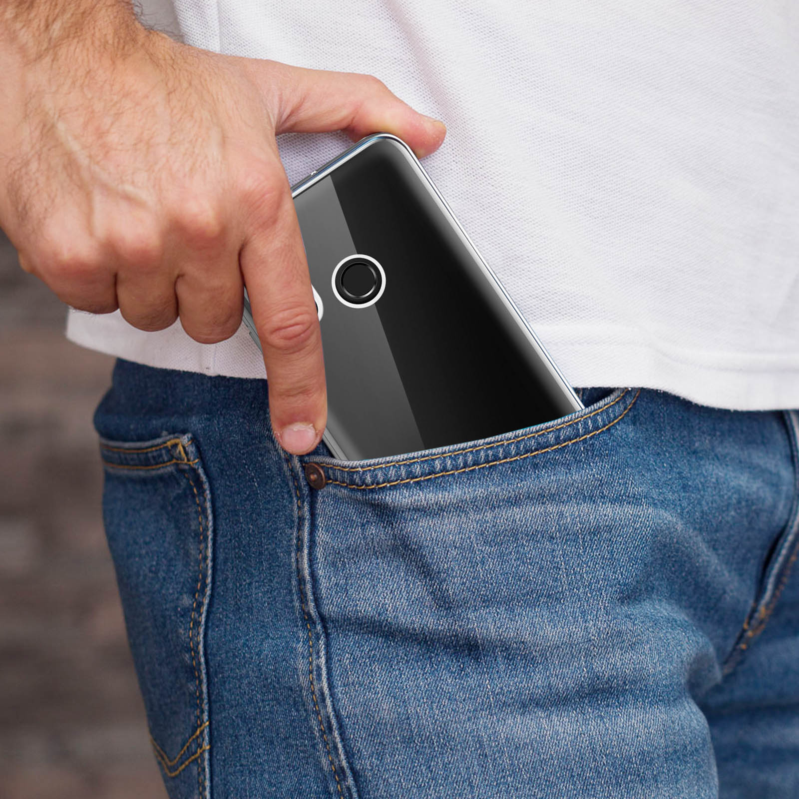 Una mano che mette un telefono nero con custodia trasparente in una tasca dei jeans.