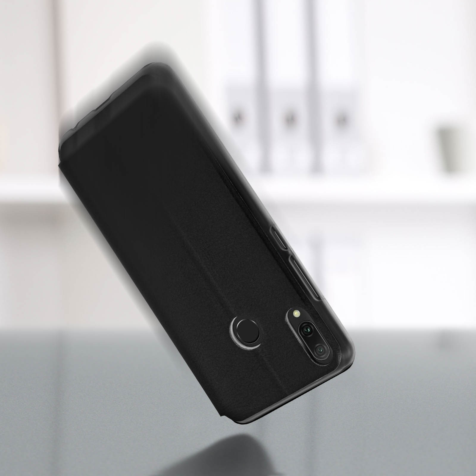 Funda negra para teléfono sobre una superficie gris. El teléfono está ligeramente inclinado, con la parte trasera hacia arriba.